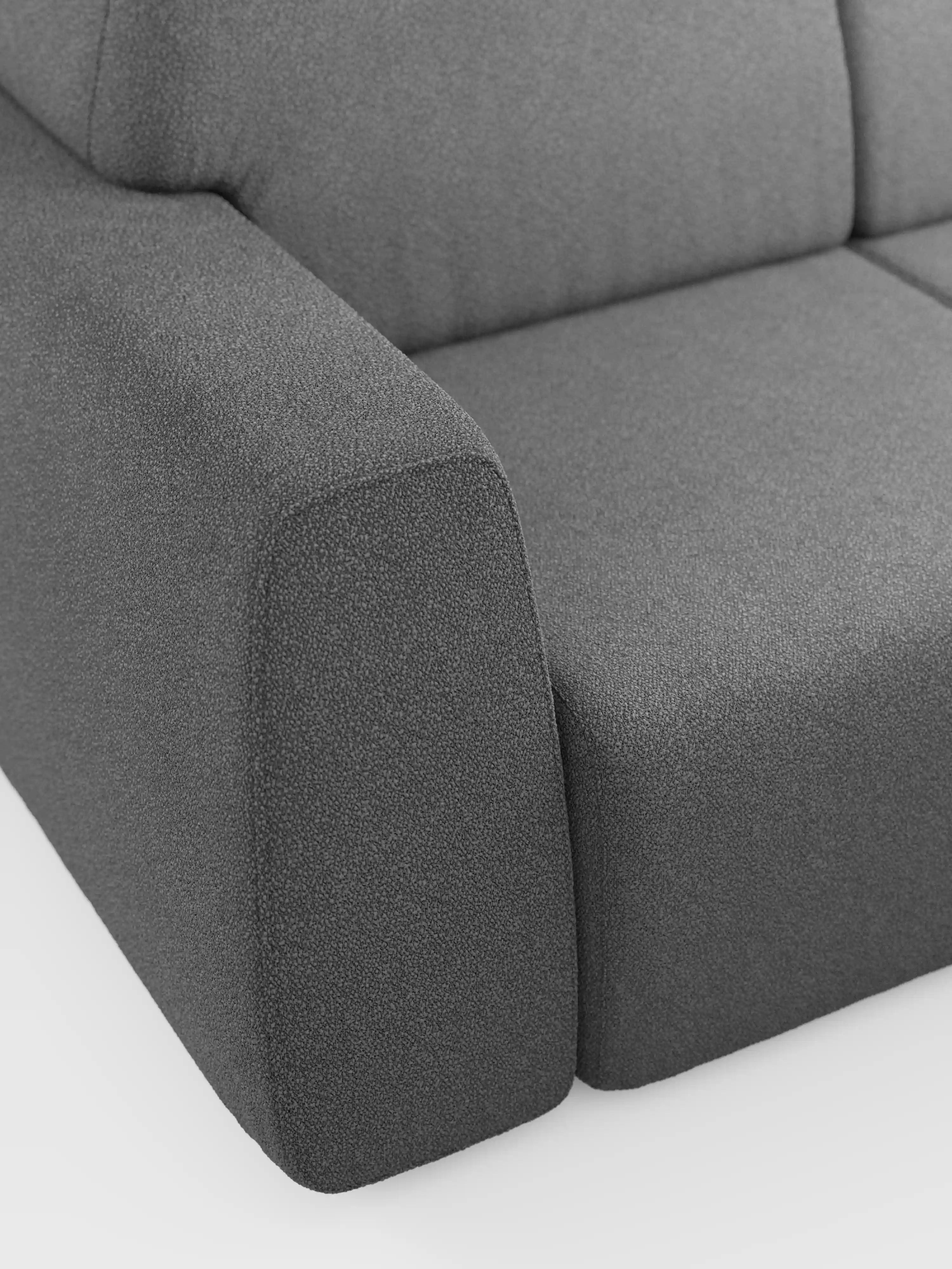 Primo piano del divano a 3 posti Orbit, modello moderno in grigio scuro di Divani.Store, caratterizzato da un rivestimento completamente sfoderabile in tessuto T33 effetto cotone, facile da pulire. Sono visibili l’ampio bracciolo rettangolare e parte del cuscino di seduta, che mettono in risalto la trama del rivestimento su uno sfondo bianco a tinta unita, esaltando il design pulito e minimalista del divano.