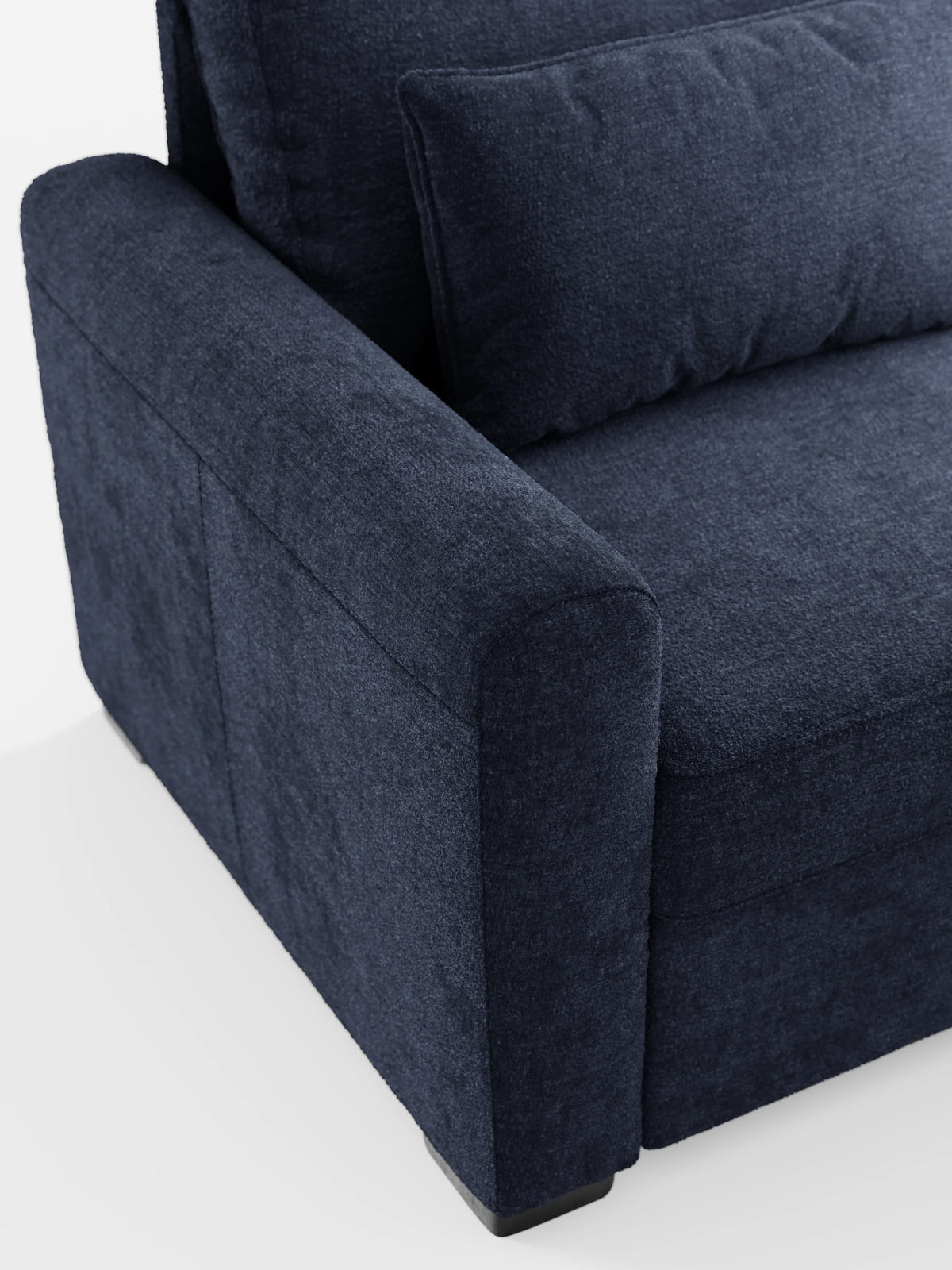 Un primo piano di un divano letto Ottaviano blu navy con letto estraibile – penisola reversibile e contenitore in tessuto materico smacchiabile, con particolare attenzione al bracciolo sinistro dalla trama particolare e a un cuscino rettangolare coordinato su sfondo bianco.