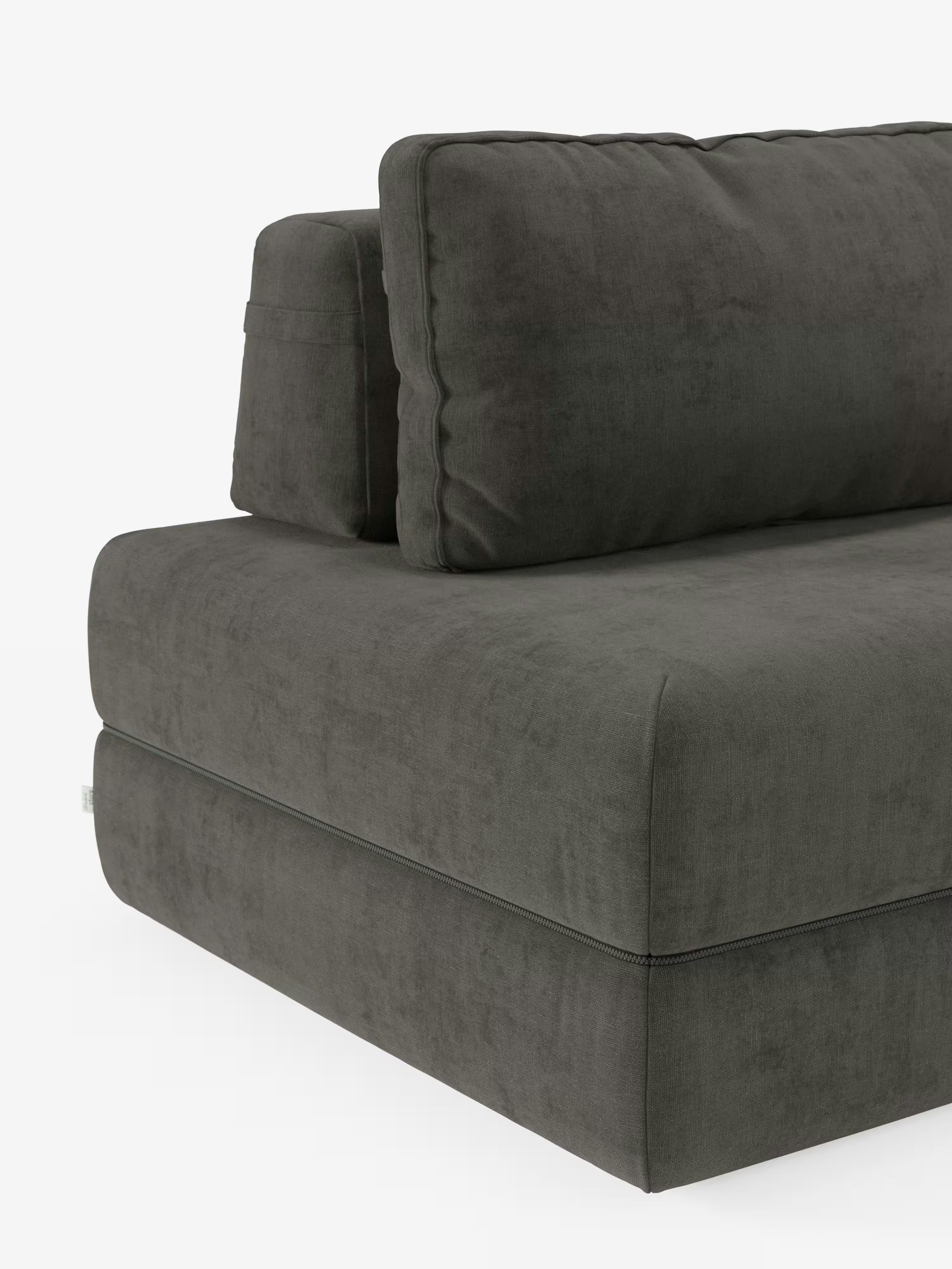 Un primo piano del divano letto matrimoniale Rift a 2 e 3 posti di Divani.Store in grigio scuro, rivestito in tessuto T31 dall’effetto vellutato e facile da pulire. L’immagine mette in risalto i cuscini della seduta e dello schienale, spessi e morbidi, con cuciture semplici che ne accentuano la consistenza soffice e la moderna silhouette squadrata. Gli schienali mobili offrono un comfort flessibile e il divano è dotato di un materasso in memory foam alto 24 cm. Lo sfondo è bianco a tinta unita.