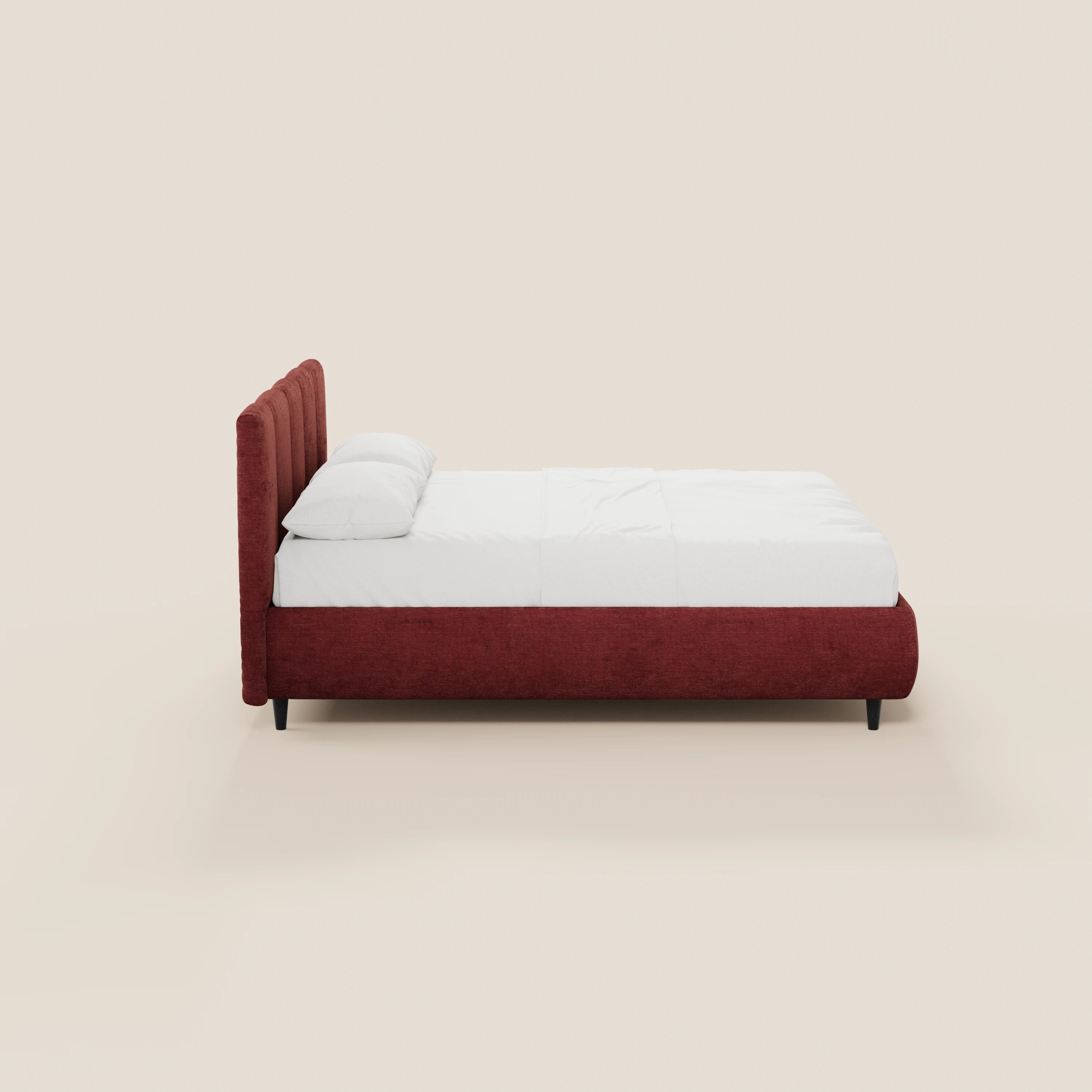 Una vista laterale del letto imbottito ARKAM di Letti.store, caratterizzato da una struttura rivestita in tessuto Oeko-Tex® rosso intenso e da una testiera con cuciture verticali, biancheria da letto e cuscini bianchi, su gambe corte nere su uno sfondo beige chiaro.