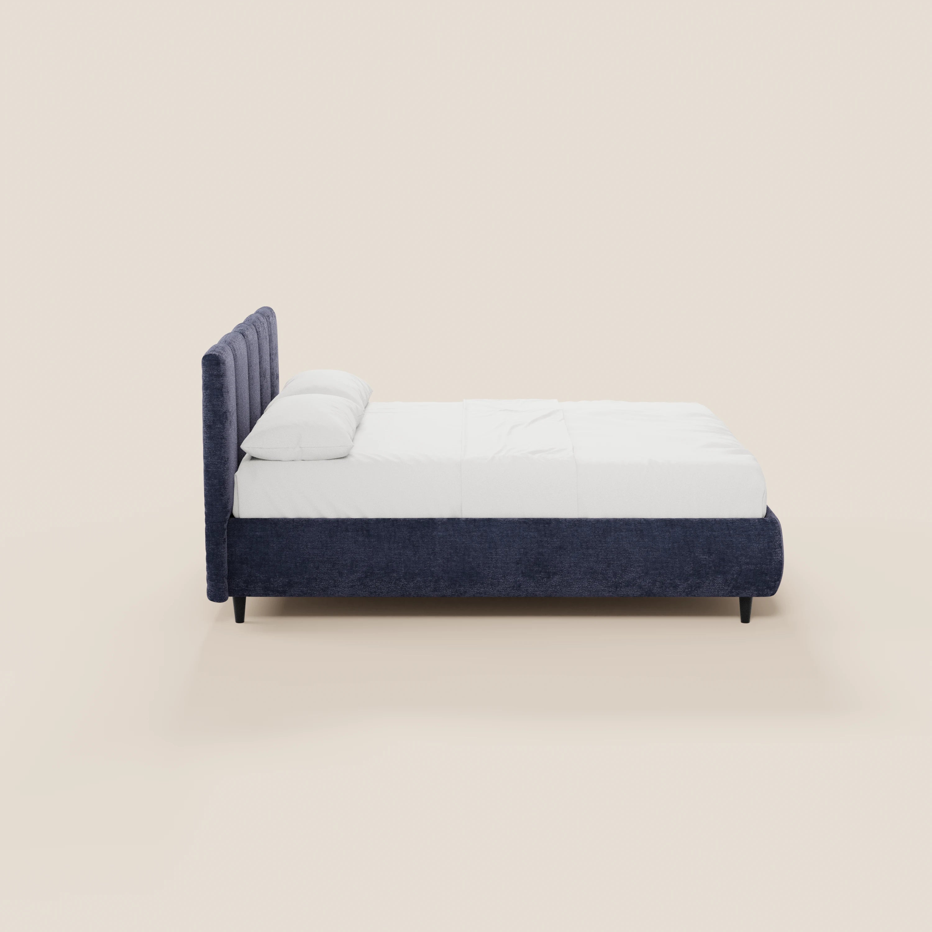 Il letto imbottito ARKAM di Letti.store presenta una struttura rivestita in blu scuro certificata Oeko-Tex®, una testiera con cuciture verticali, biancheria da letto bianca e due cuscini. Il suo design minimal in stile shabby chic è raffigurato di profilo su uno sfondo beige chiaro.