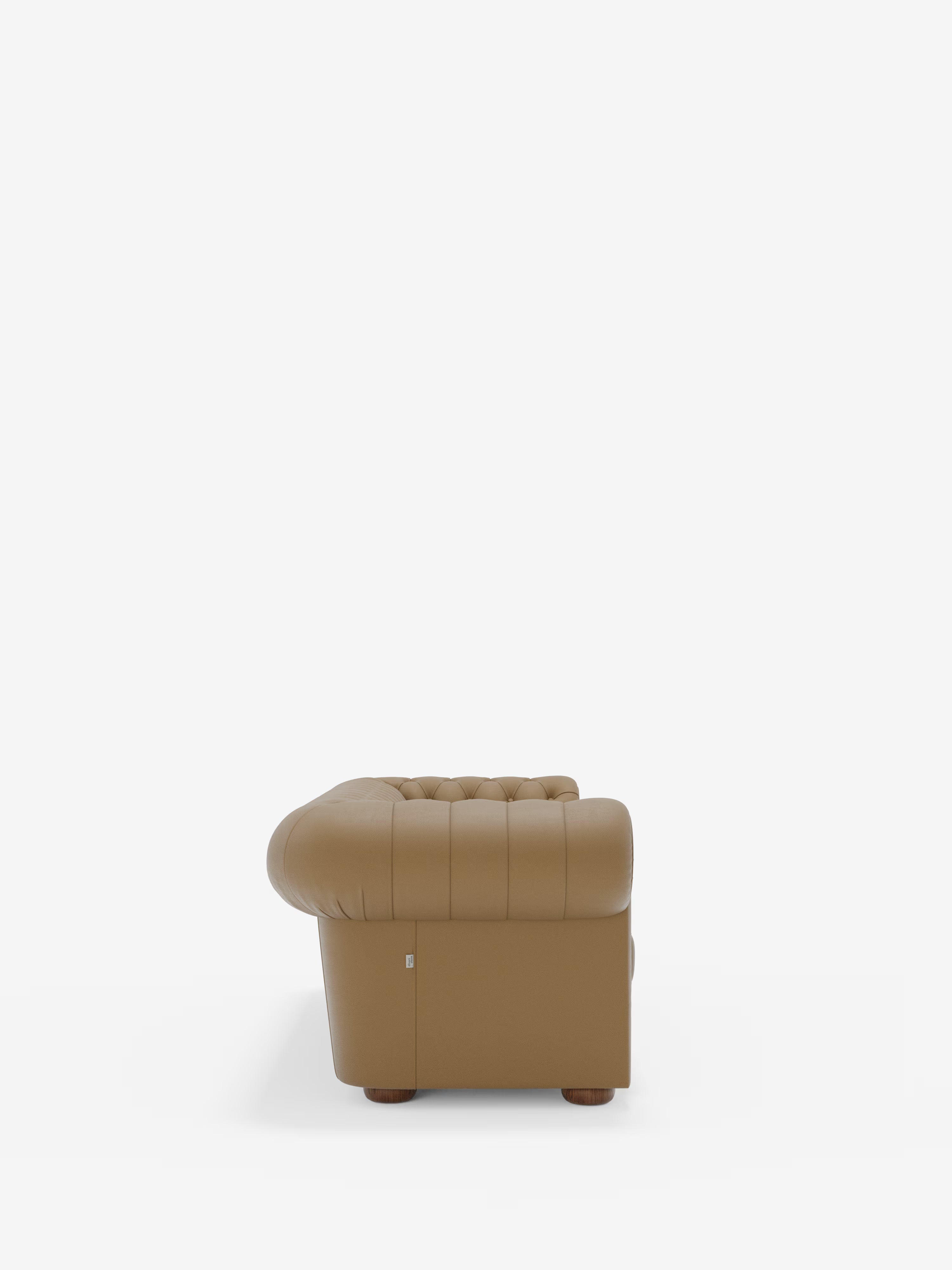 Vista laterale del Chester – Divano Chesterfield in vera pelle spessorata a 2 e 3 posti di Divani.Store, una poltrona in pelle marrone trapuntata caratterizzata da braccioli e schienale classici arrotondati, piedini in legno e rivestimento in vera pelle liscia, in primo piano su uno sfondo bianco a tinta unita.