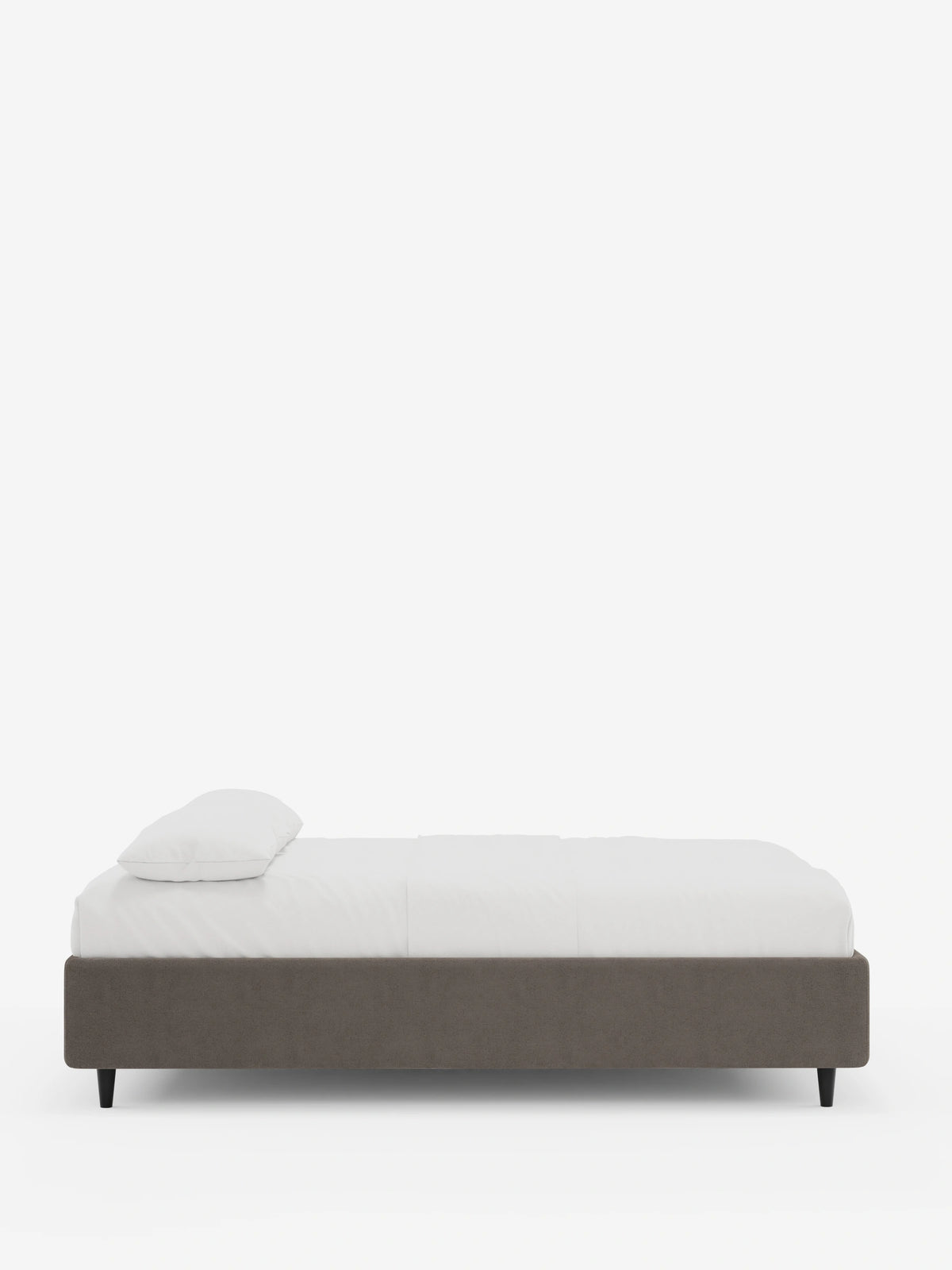Vista laterale di un letto sommier imbottito ERON con contenitore, rivestito in tessuto impermeabile certificato Oeko-Tex di colore grigio scuro, con biancheria da letto bianca e un unico cuscino, poggiato su quattro sottili gambe nere su uno sfondo bianco.