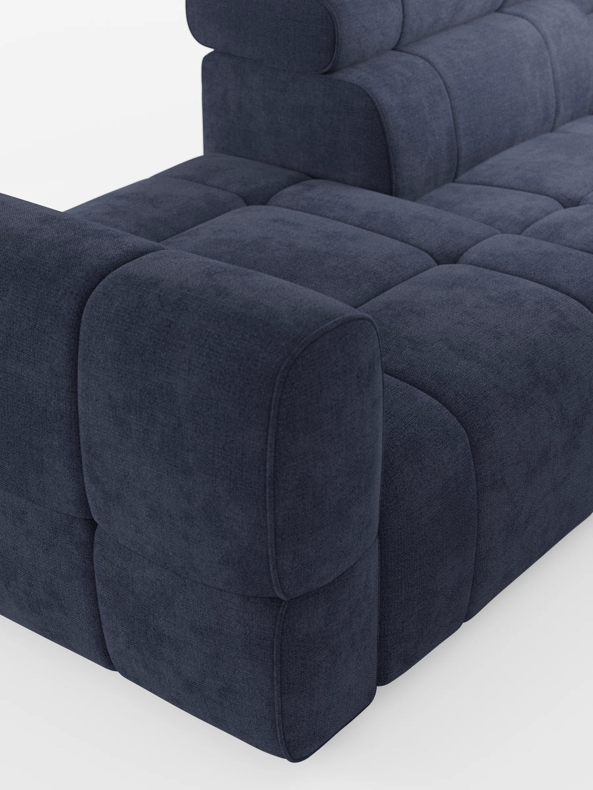 Un divano componibile Giotto Divano blu scuro con terminale aperto – opzione relax elettrico in tessuto smacchiabile T23: divano angolare con motivo a griglia trapuntato, braccioli arrotondati e squadrati e schienale imbottito su uno sfondo chiaro.