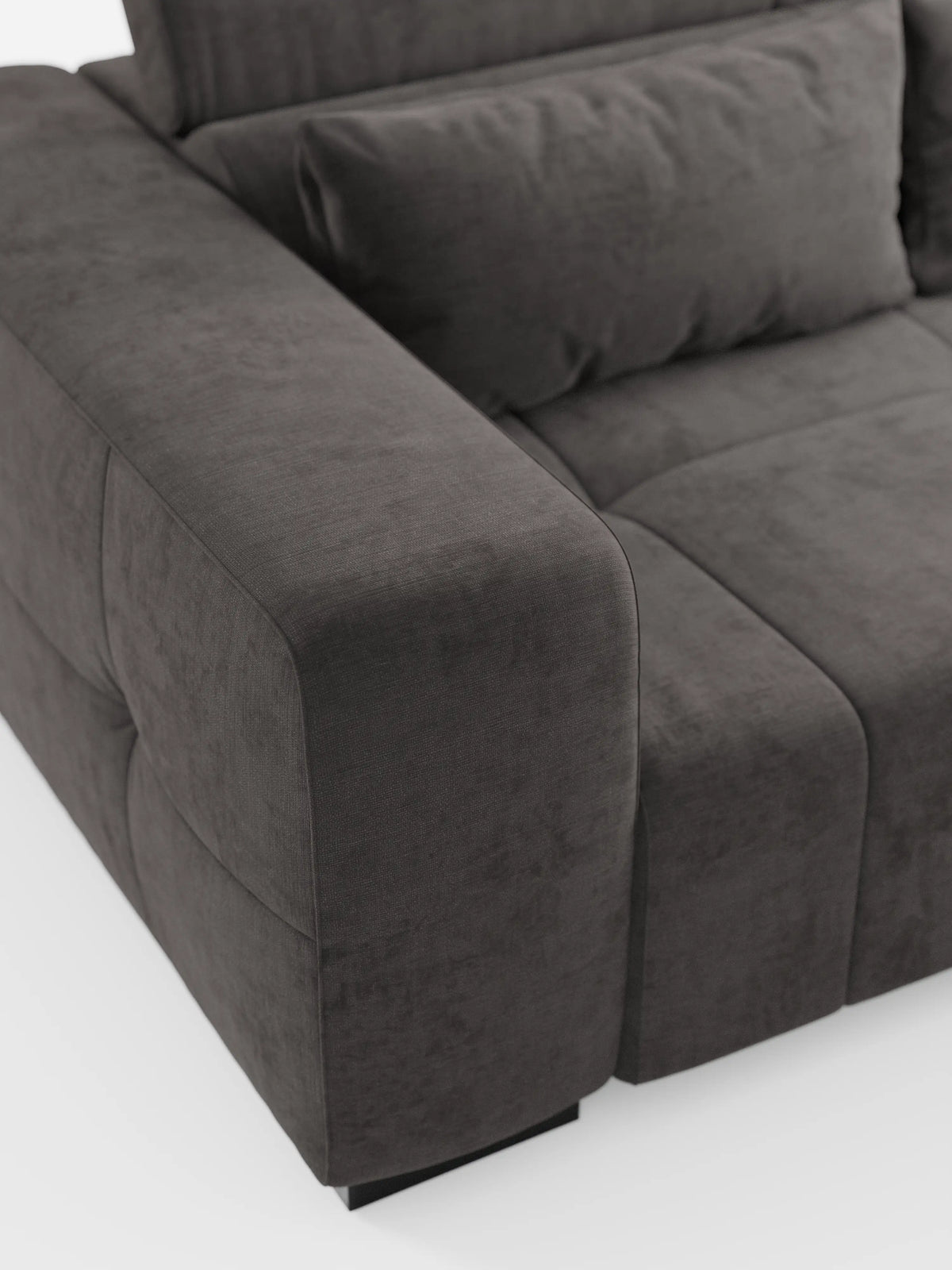 Primo piano del divano Monarch con funzione relax elettrica per l’allungamento delle sedute e poggiatesta reclinabile di Divani.Store, presentato in un moderno tessuto T31 grigio scuro, leggermente testurizzato, morbido e facile da pulire. L'immagine mette in risalto i suoi ampi braccioli, lo schienale imbottito e la seduta, con il divano sostenuto da piccole gambe nere su uno sfondo bianco a tinta unita.