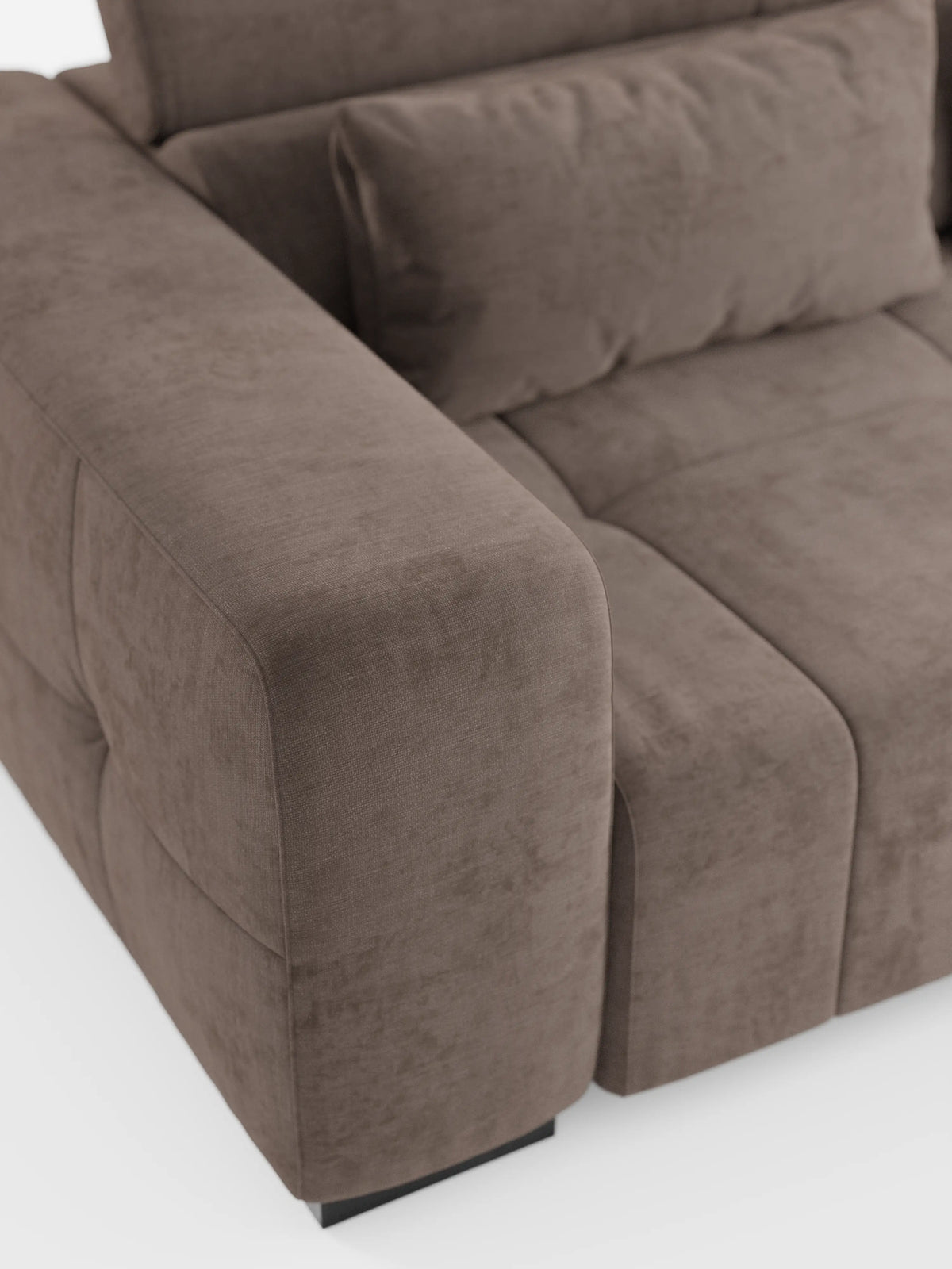 Primo piano del divano angolare Monarch con penisola e funzione Relax Elettrico per l’allungamento delle sedute di Divani.Store, dotato di poggiatesta reclinabili in morbido tessuto T31 resistente alle macchie. L’immagine mette in risalto i cuscini dei braccioli, della seduta e dello schienale, caratterizzati da una texture soffice, cuciture a vista e linee pulite. Il divano poggia su piedini neri corti su uno sfondo bianco.
