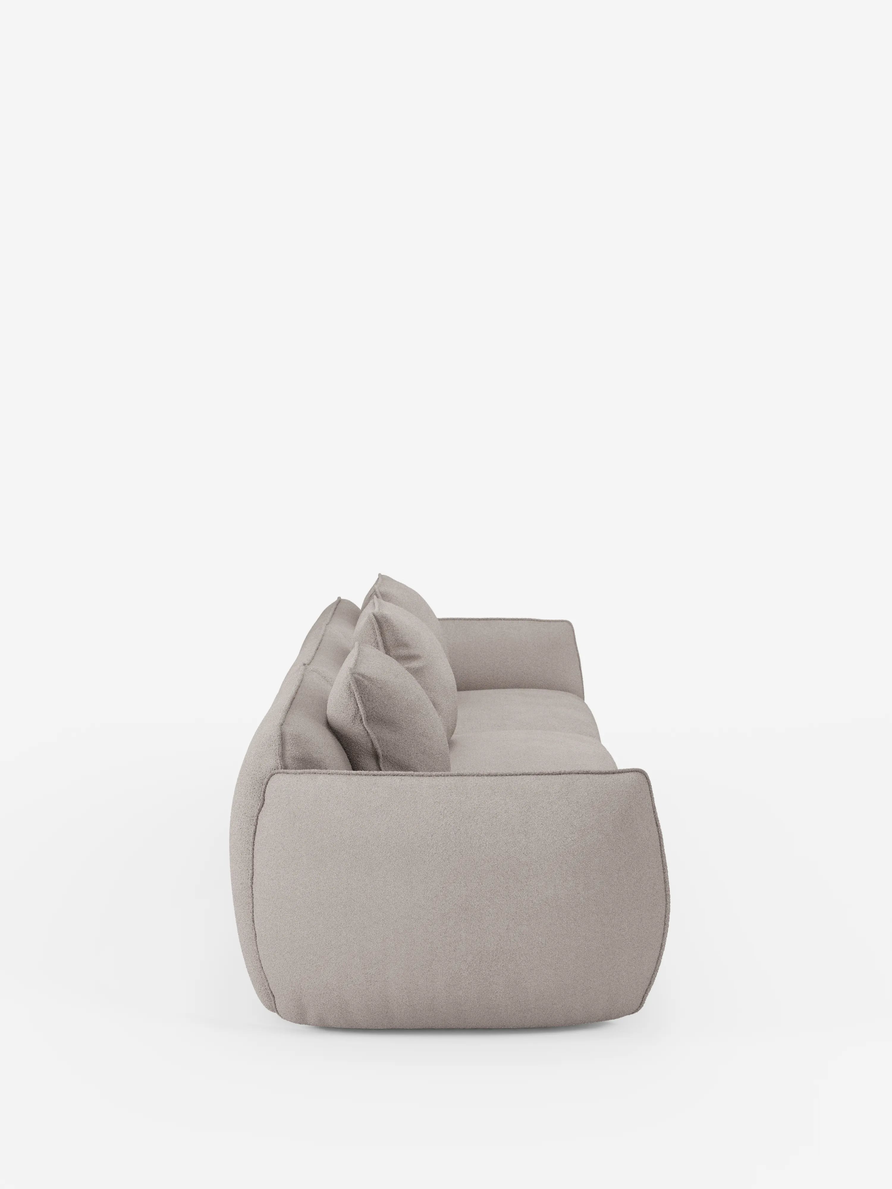 Vista laterale del divano modulare a 3 posti Nimbus di Divani.Store, qui raffigurato in grigio chiaro con morbidi cuscini e un design arrotondato e delicato. Realizzato in tessuto T33 effetto cotone di facile pulizia, questo divano modulare si presenta con un profilo basso su uno sfondo bianco a tinta unita, che ne esalta lo stile semplice e contemporaneo.