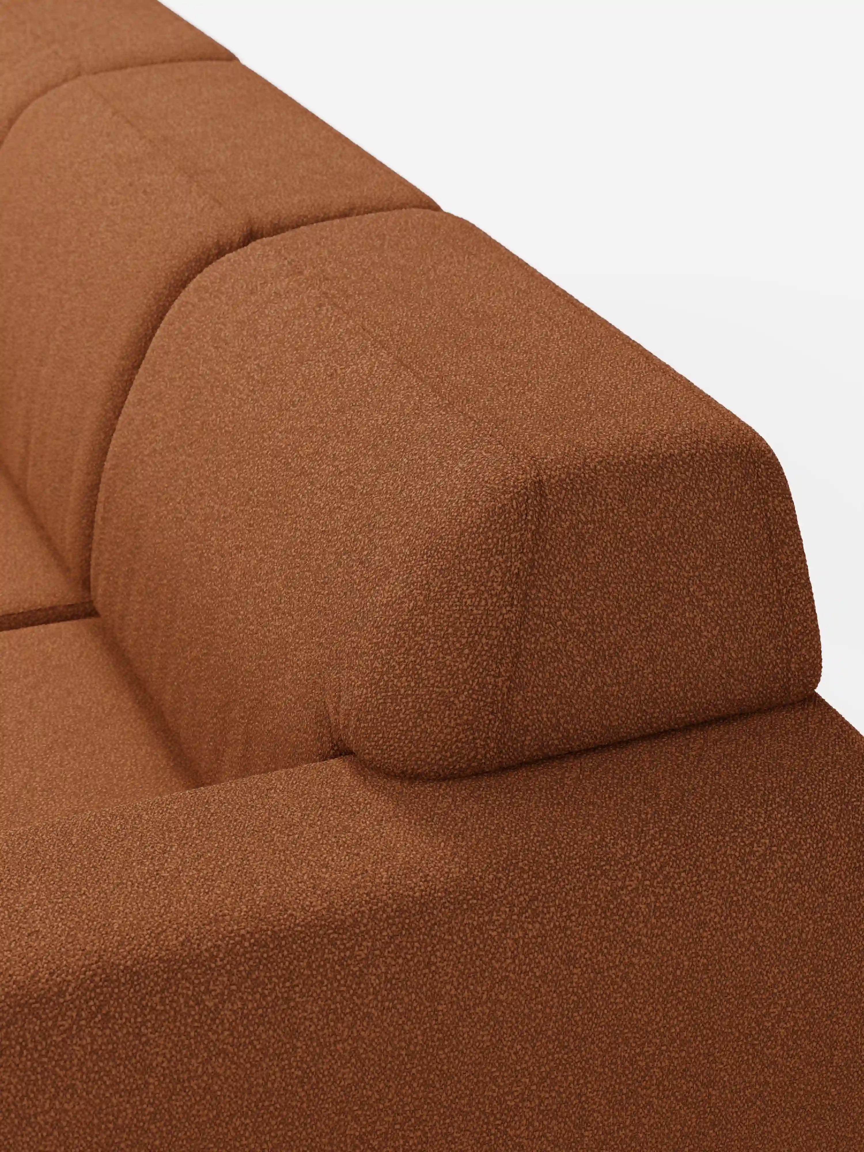 Primo piano del divano Orbit con 3 sedute scorrevoli e allungabili di Divani.Store, caratterizzato da un rivestimento color ruggine con texture, realizzato in tessuto smacchiabile T33 effetto cotone. L’immagine mette in risalto lo schienale e il cuscino di seduta dalle forme delicatamente arrotondate, attirando l’attenzione sul motivo discreto del tessuto e sulle linee pulite e geometriche del divano, che risaltano sullo sfondo bianco a tinta unita.