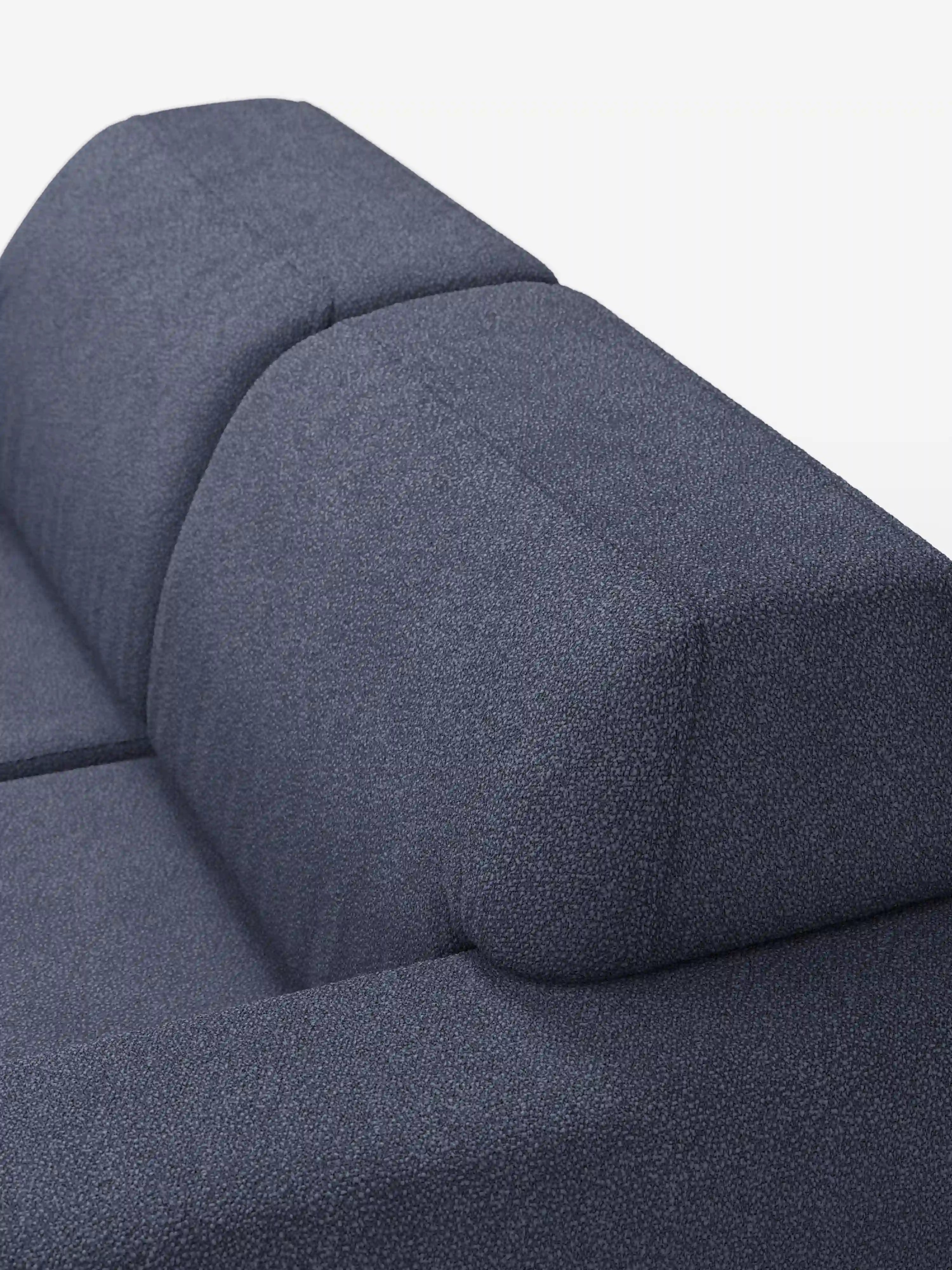 Primo piano del divano a 3 posti Orbit di Divani.Store, un divano moderno di colore blu scuro rivestito in tessuto T33 resistente alle macchie e dall’effetto cotone. L’immagine mette in risalto il rivestimento testurizzato, gli ampi braccioli e lo schienale leggermente inclinato su uno sfondo bianco. È visibile solo la parte superiore di questo elegante modello dal design contemporaneo.