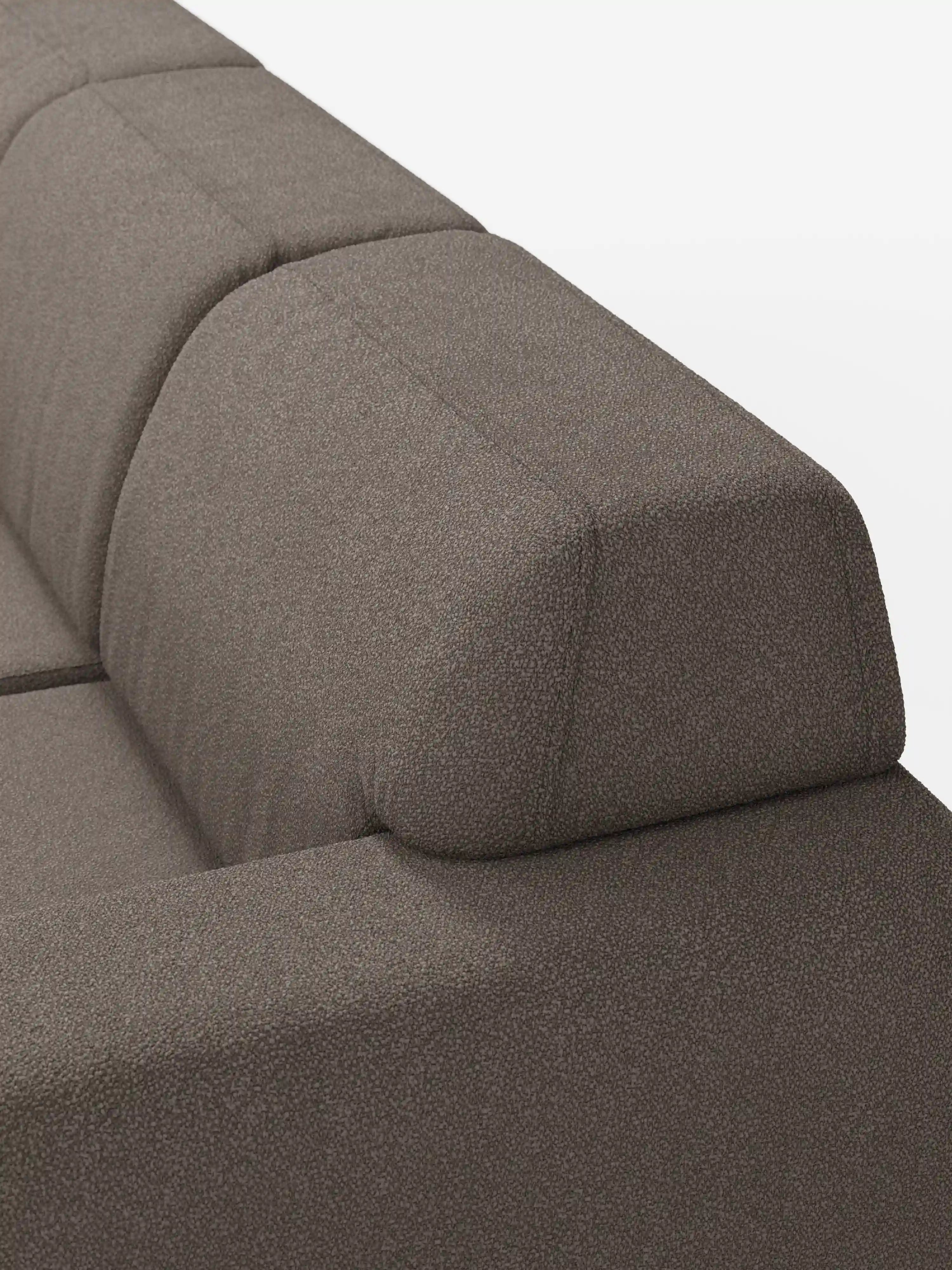 Primo piano del divano angolare Orbit con penisola reversibile e tutte le sedute allungabili di Divani.Store, rivestito in tessuto T33 smacchiabile effetto cotone. I braccioli e lo schienale squadrati e angolari ne sottolineano il design moderno e minimalista, mentre il rivestimento dalla trama delicata e la morbida imbottitura evocano il comfort raffinato tipico di un divano di alta gamma. Immagine su sfondo bianco.