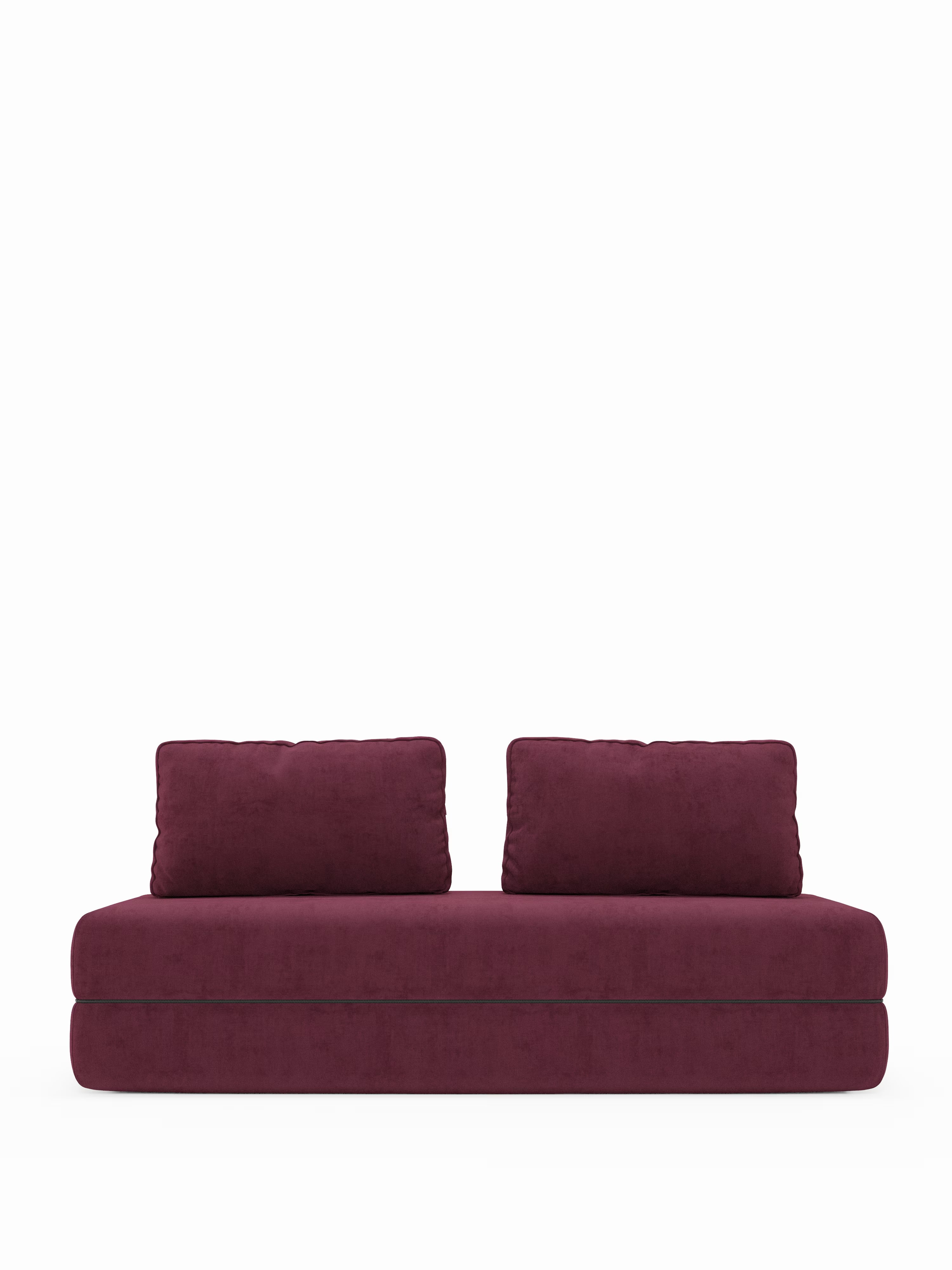 Un divano letto matrimoniale a 2 posti Rift in stile contemporaneo di Divani.Store, rivestito in tessuto bordeaux e dotato di due grandi cuscini dello schienale abbinati. Questo divano dal design minimalista e squadrato, con schienali mobili e un materasso in memory foam (T31) alto 22 cm, è privo di gambe a vista, creando una silhouette solida e ben ancorata su uno sfondo bianco a tinta unita.