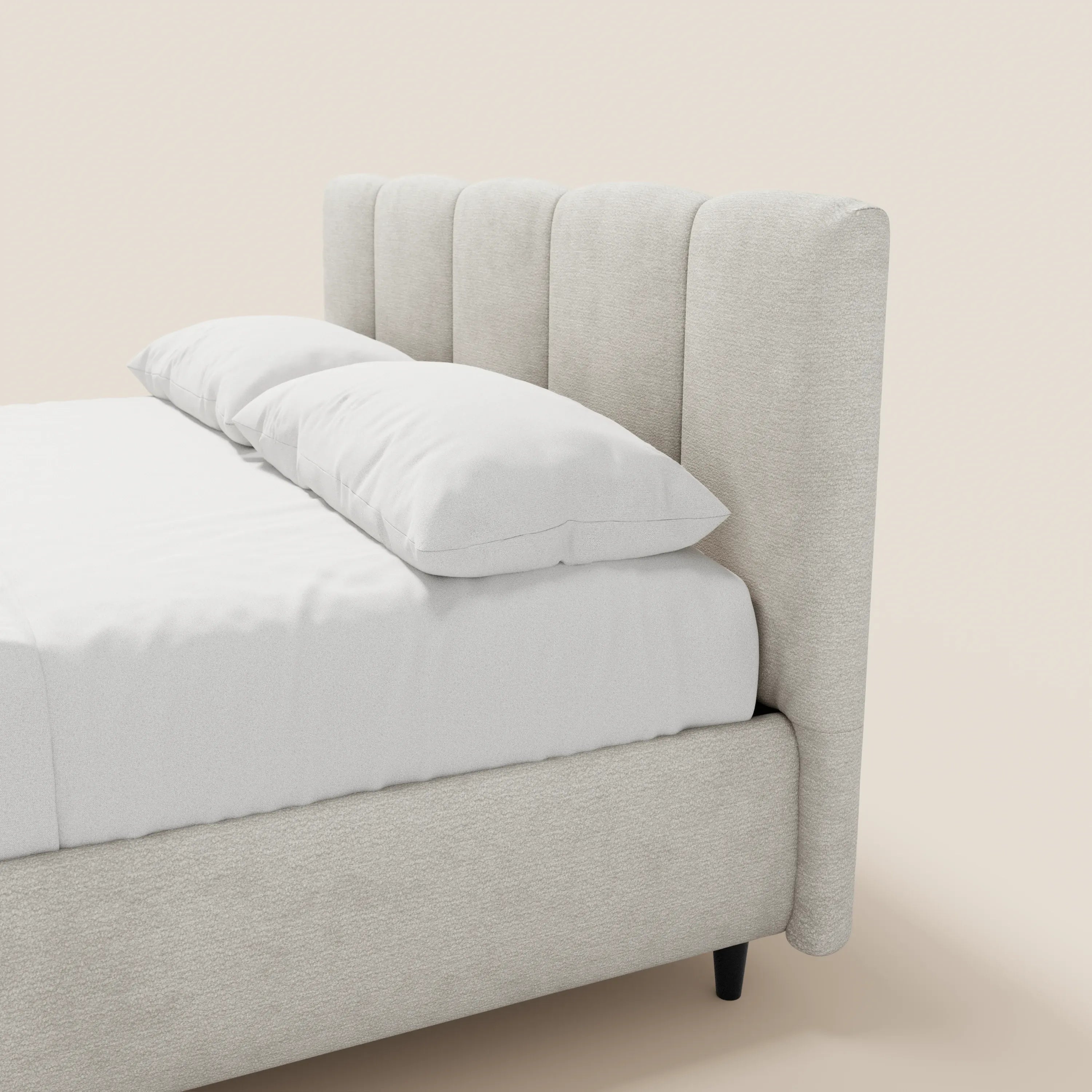 Un primo piano del letto imbottito ARKAM di Letti.store, caratterizzato da una testiera alta con cuciture verticali, in tessuto beige chiaro e certificata Oeko-Tex®. Il letto in stile shabby chic è rivestito con lenzuola bianche e presenta gambe corte di colore scuro; è raffigurato su uno sfondo a tinta unita.