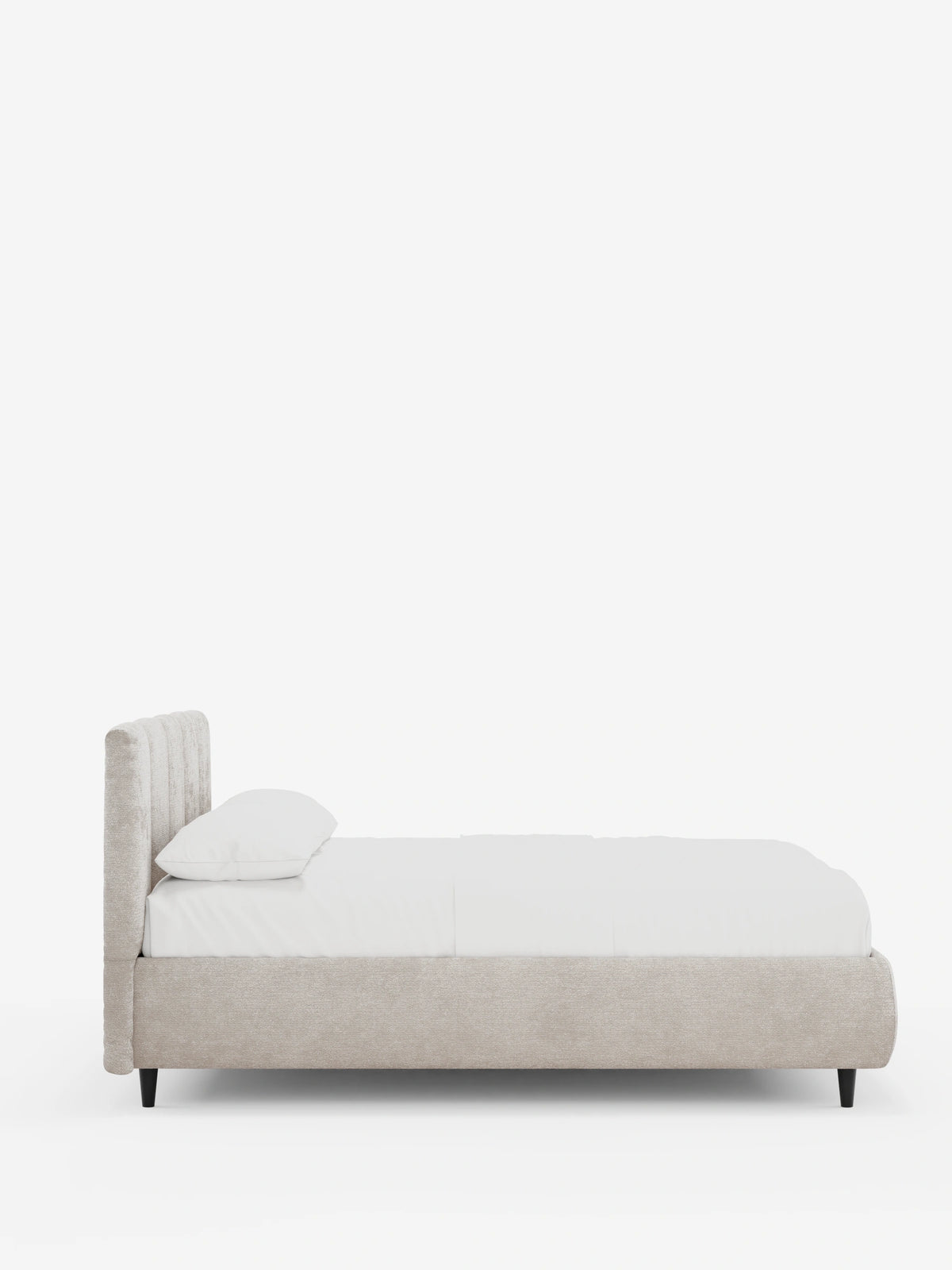 Vista laterale di un letto imbottito ARKAM con contenitore e testiera a cuciture verticali in beige chiaro, caratterizzato da un’alta testiera con cuciture verticali, biancheria da letto bianca, un cuscino e gambe corte nere su uno sfondo bianco a tinta unita.