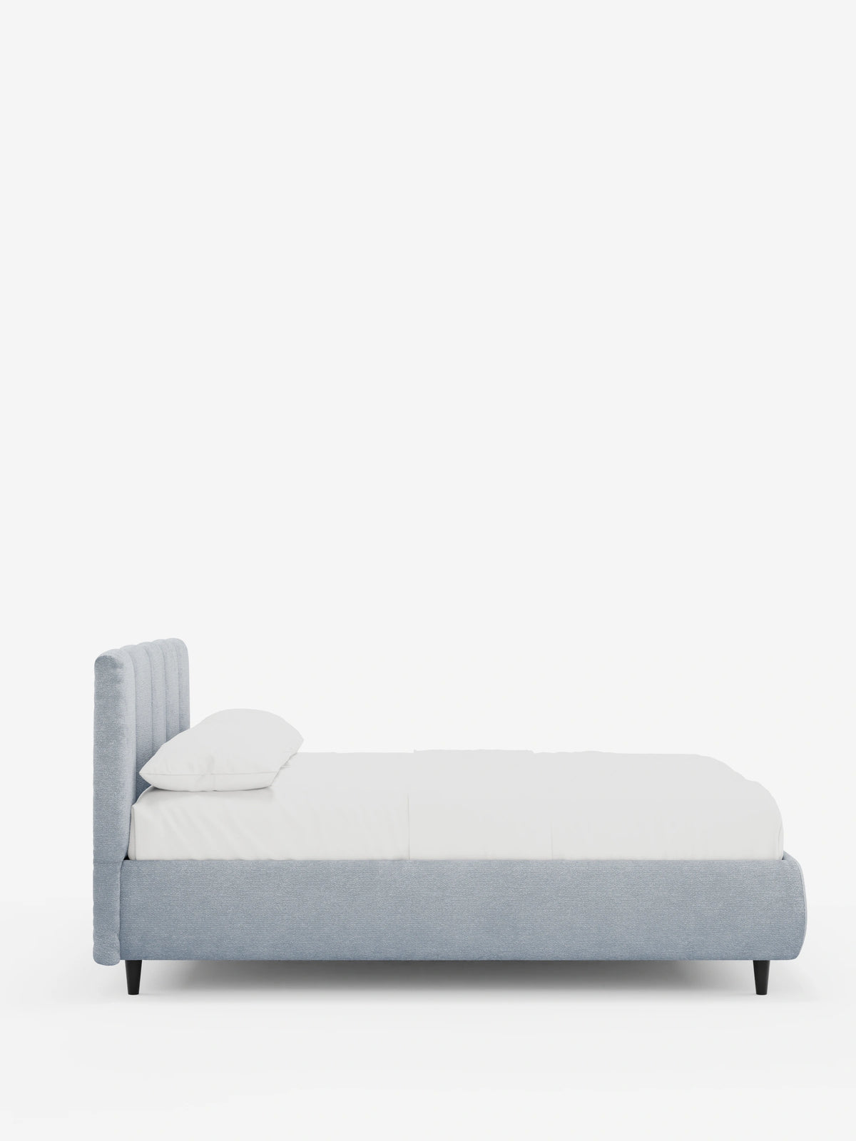 Vista laterale di un letto imbottito ARKAM azzurro con contenitore e testiera a cuciture verticali, materasso bianco e quattro gambe corte, scure e affusolate, su uno sfondo bianco a tinta unita.