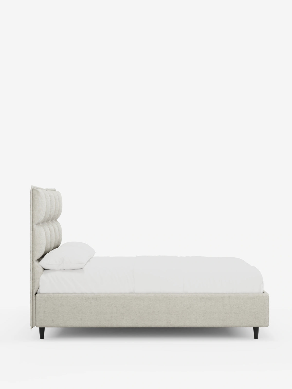 Una vista laterale del letto imbottito AURO con contenitore e testiera alta capitonné in ciniglia Oeko-Tex®, un letto imbottito beige con testiera alta capitonné, lenzuola bianche e gambe corte e affusolate di colore nero su uno sfondo bianco.