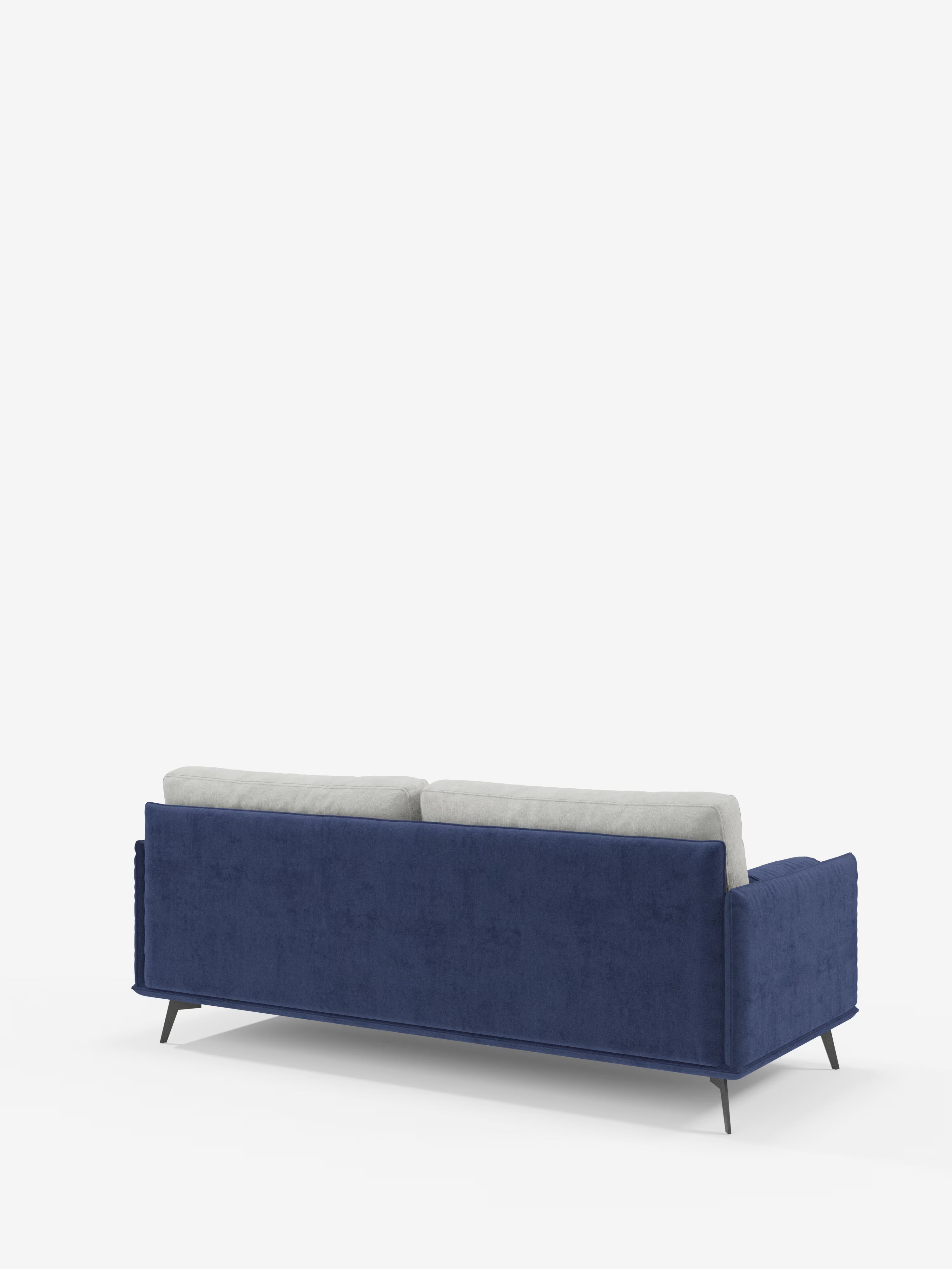 Il divano Basalto a 2 o 3 posti bicolore di Divani.Store — un divano moderno caratterizzato da schienale e fianchi rivestiti in tessuto T31 blu scuro antimacchia, base sottile in metallo nero e due cuscini dello schienale imbottiti in piuma di colore grigio chiaro — è ripreso da dietro con una leggera angolazione su uno sfondo bianco.