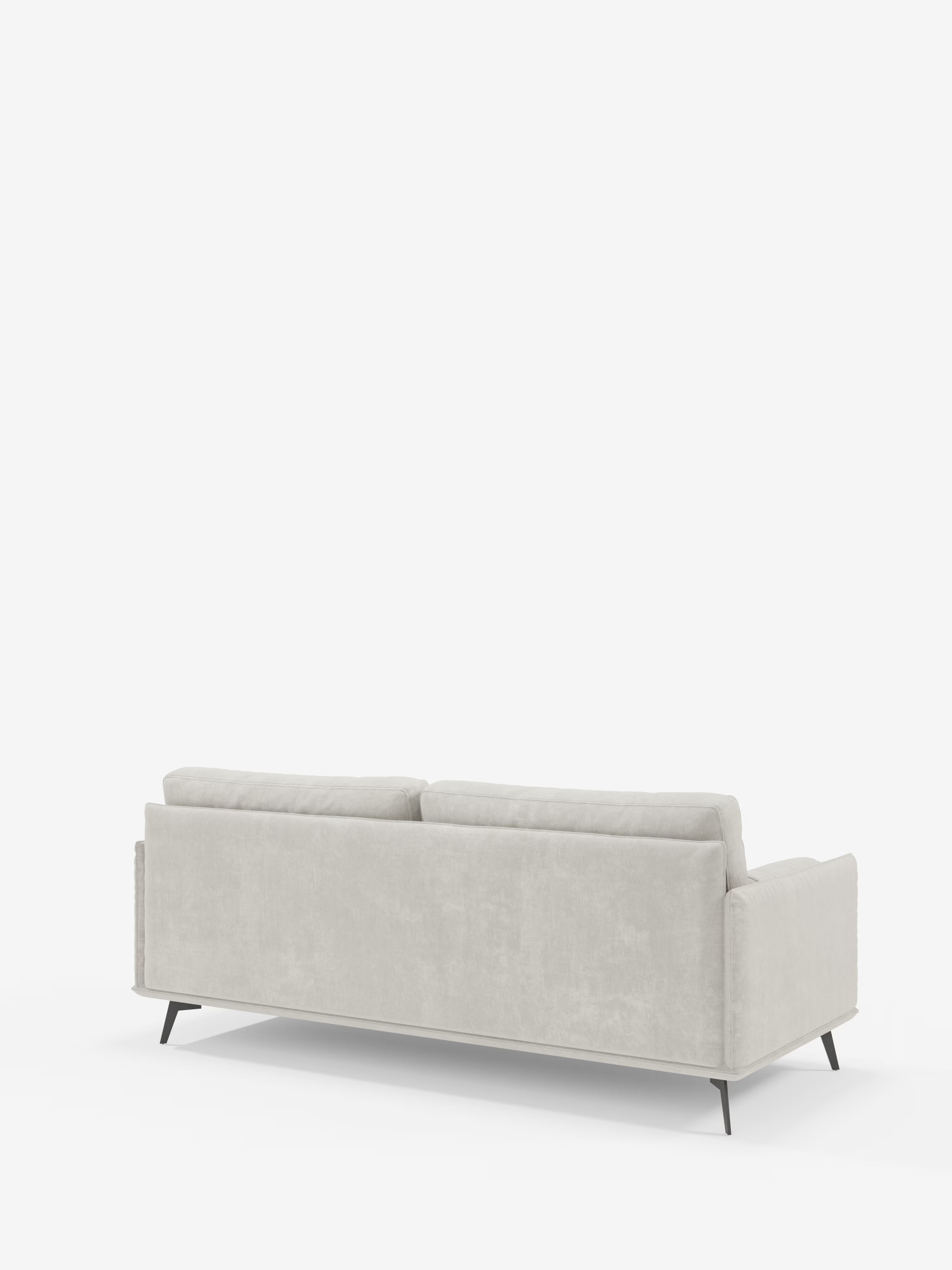Nella foto, vista dal retro, il divano lineare Basalto a 2 o 3 posti di Divani.Store, in un elegante grigio chiaro, che mette in risalto la sua silhouette moderna e minimalista con morbidi cuscini e sottili gambe in metallo nero. Il rivestimento sfoderabile in tessuto T31 smacchiabile garantisce praticità, mentre lo sfondo bianco a tinta unita mantiene l’attenzione esclusivamente sul design raffinato del divano.
