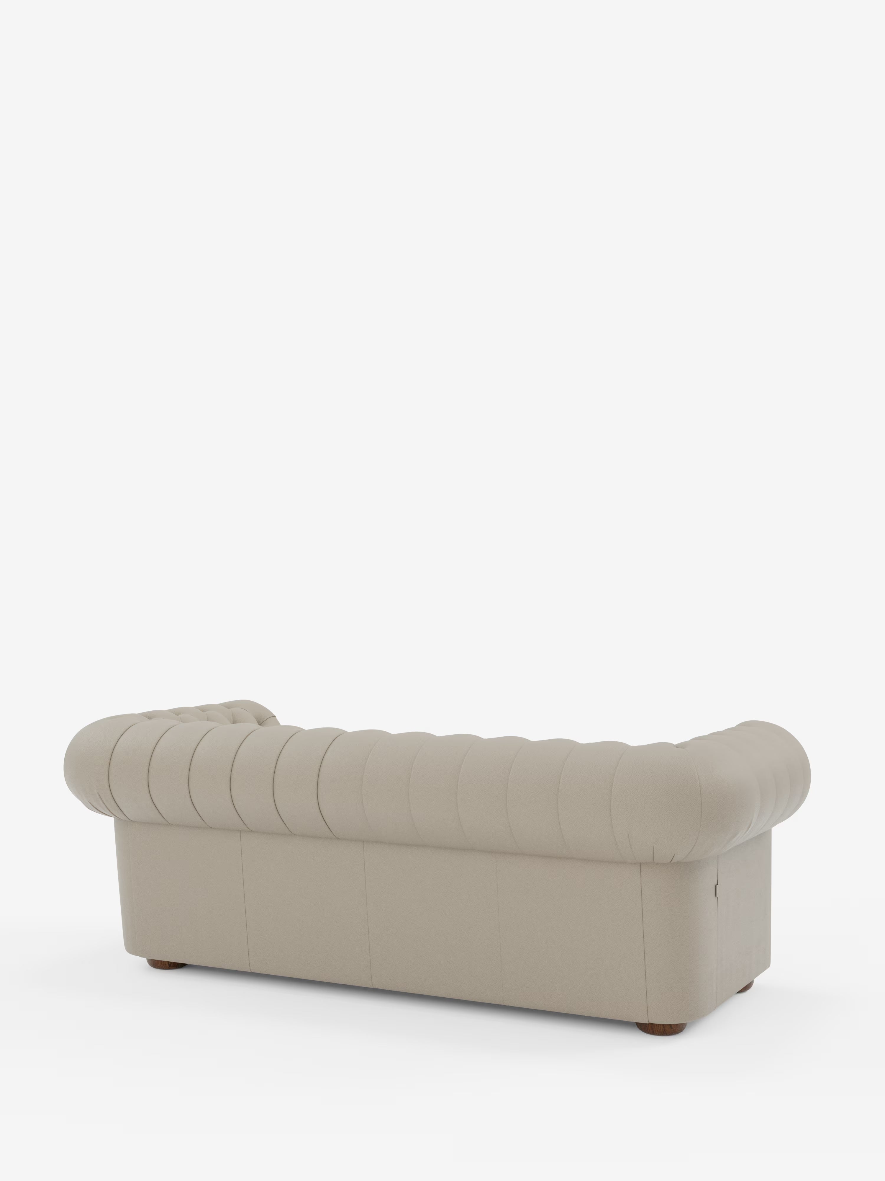 Un Chesterfield beige – Divano Chesterfield in vera pelle spessorata a 2 e 3 posti di Divani.Store, caratterizzato da rivestimento in vera pelle trapuntata con cuciture verticali, braccioli e schienale arrotondati, piedini corti e rotondi in legno e un elegante design Made in Italy; raffigurato di retro su sfondo bianco.