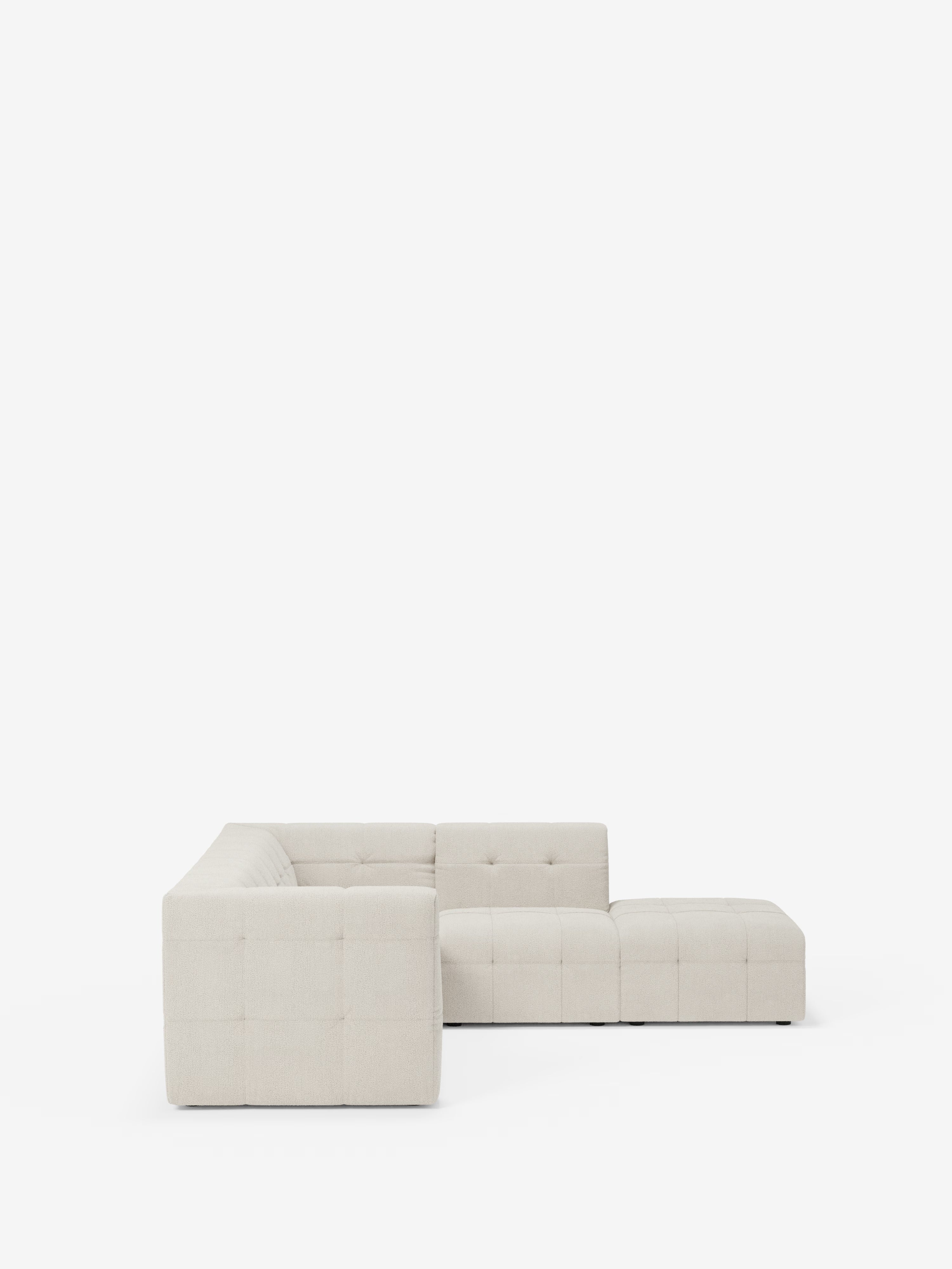 Un divano angolare componibile e modulare Mosaic di colore beige, in bouclé: capitonné e design in tessuto smacchiabile T21 di Divani.Store, è esposto su uno sfondo bianco a tinta unita e visto di profilo. Caratterizzato da uno schienale basso, un rivestimento capitonné in raffinato bouclé, linee pulite e moderne e braccioli squadrati, questo divano offre ampio spazio per ospitare diverse persone.