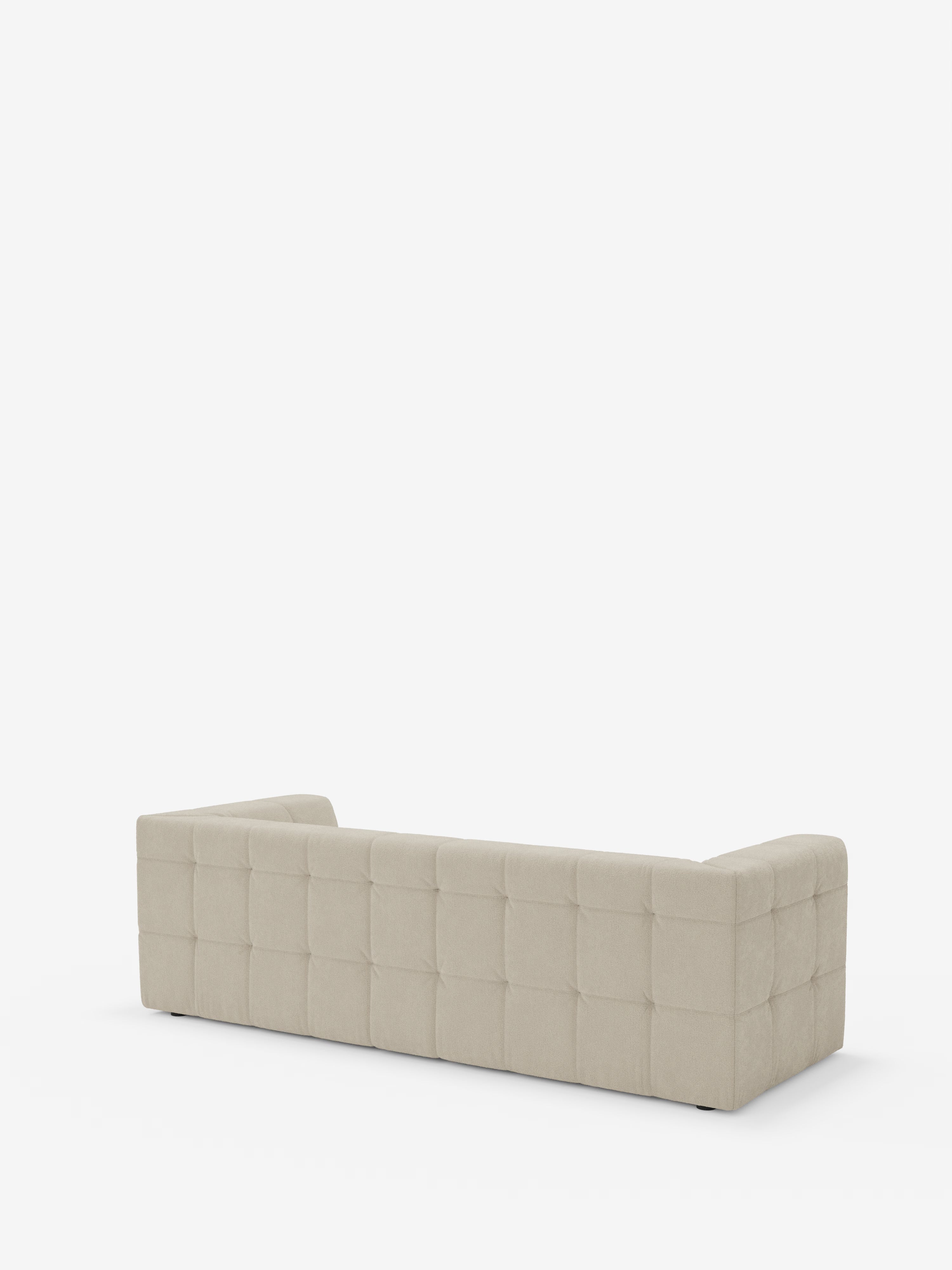 Il divano modulare Mosaic Divano a 3 e 4 posti in bouclé di Divani.Store, in una tonalità beige chiaro e dal design contemporaneo, è ripreso da dietro e presenta braccioli bassi, uno schienale rettangolare e un rivestimento trapuntato con motivo a griglia. Il divano modulare in tessuto antimacchia è ripreso su uno sfondo bianco a tinta unita, senza altri oggetti visibili.