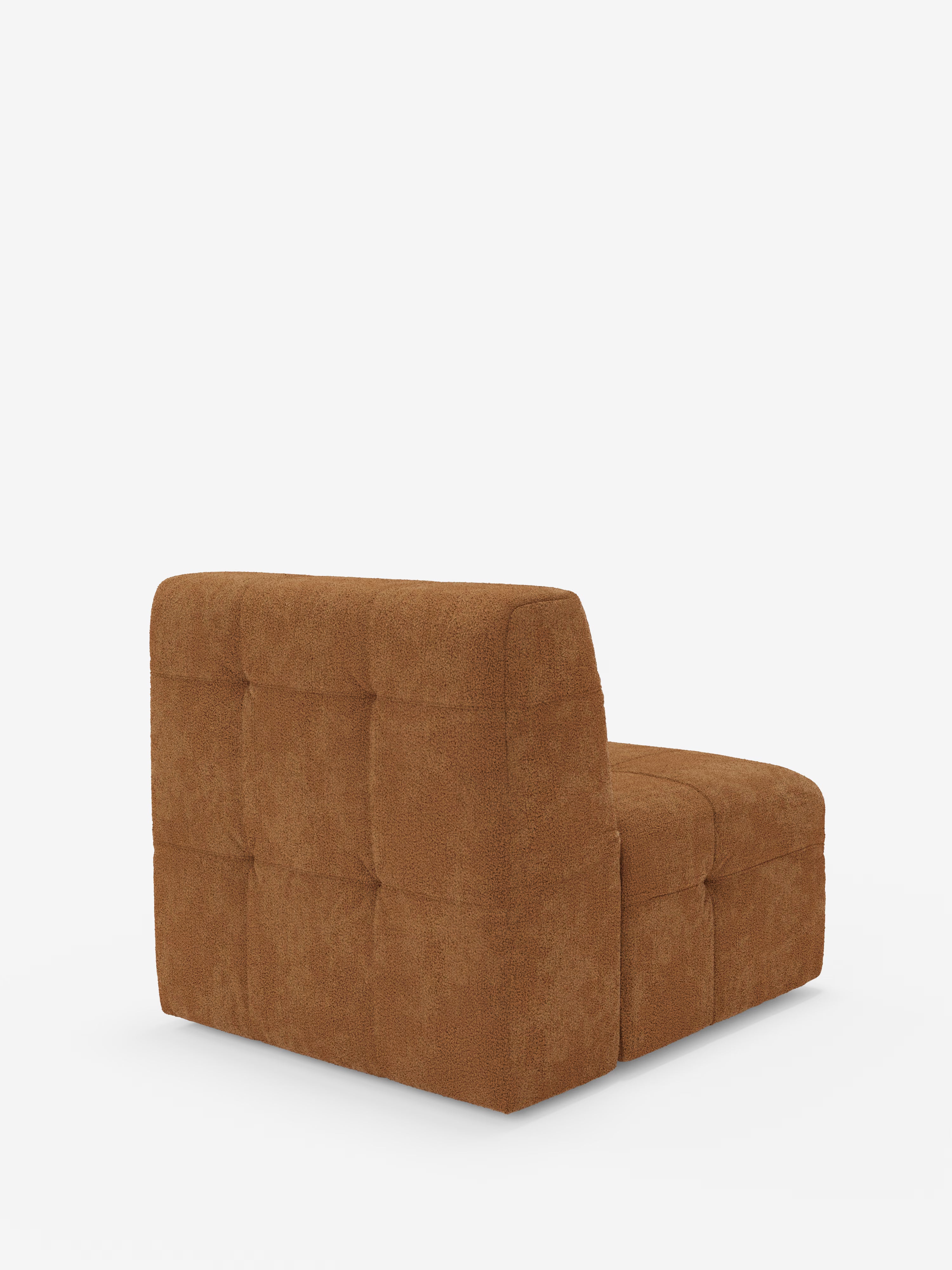Una poltrona contemporanea senza braccioli della linea Mosaic modulo di Divani.Store è raffigurata su uno sfondo bianco. Rivestita in tessuto bouclé marrone antimacchia (T21), questa poltrona da 77 cm presenta schienale e seduta bassi e capitonné, con una morbidezza testurizzata ispirata al design classico delle poltrone. La poltrona è ripresa da dietro con una leggera angolazione verso destra.