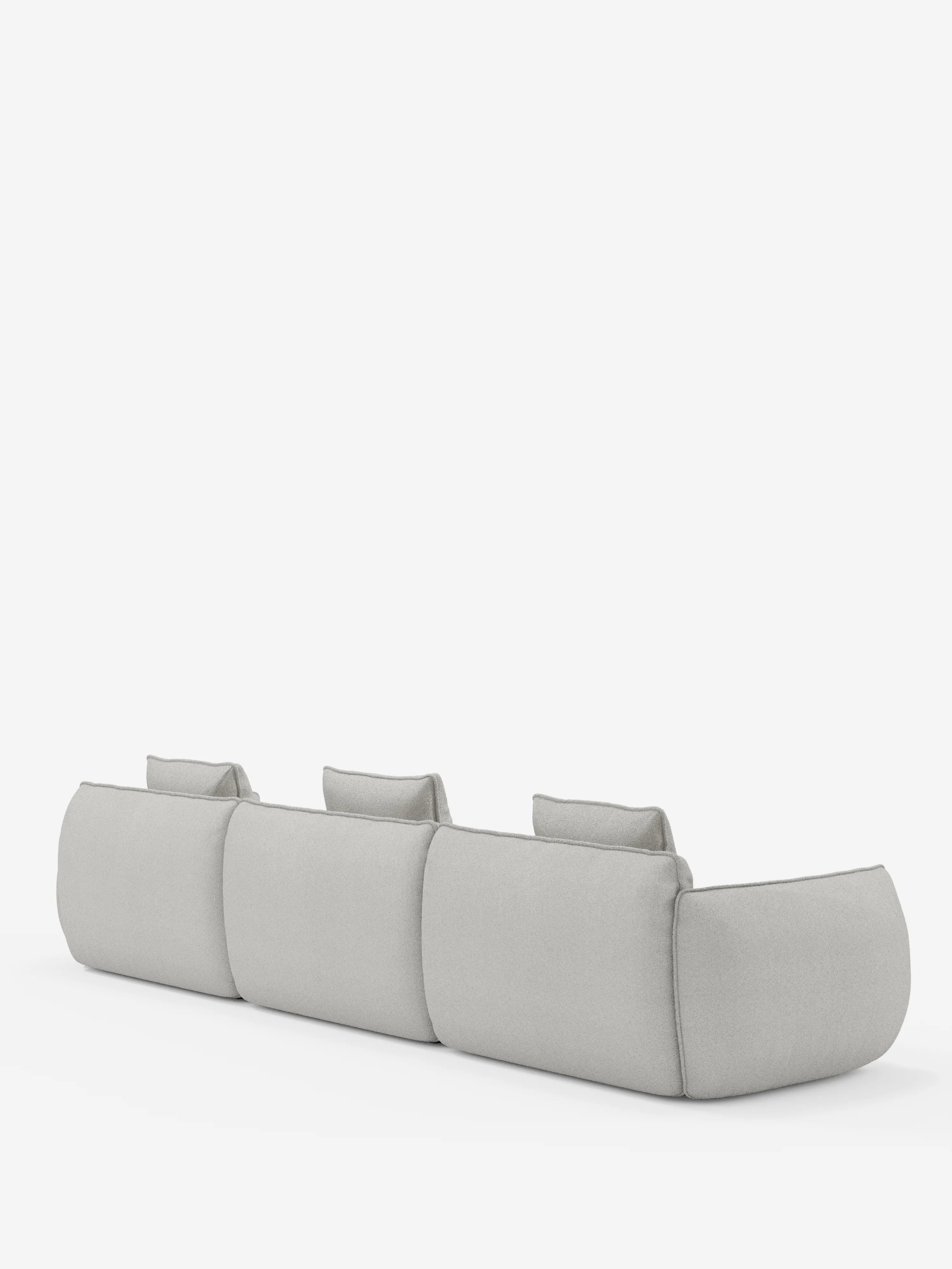 Il divano modulare a 3 posti Nimbus, realizzabile in morbido tessuto smacchiabile effetto cotone T33 di Divani.Store, è ripreso da dietro, mettendo in risalto il suo design moderno in grigio chiaro con angoli arrotondati, ampi braccioli e tre poggiatesta individuali, il tutto su uno sfondo bianco a tinta unita.