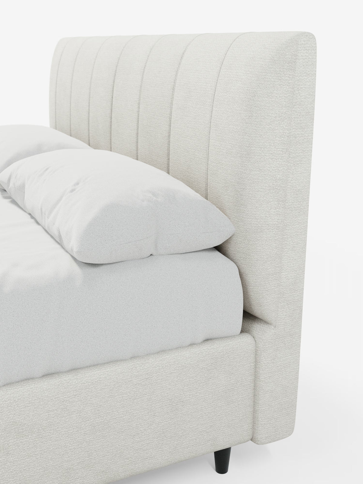 Un primo piano del letto imbottito ONYX con contenitore e testiera verticale in tessuto certificato Oeko-Tex® di Letti.store mostra un letto moderno con una testiera alta, imbottita in beige chiaro e caratterizzata da scanalature verticali. Il design presenta una base abbinata e due cuscini bianchi, che risaltano su uno sfondo bianco brillante con gambe nere parzialmente visibili.