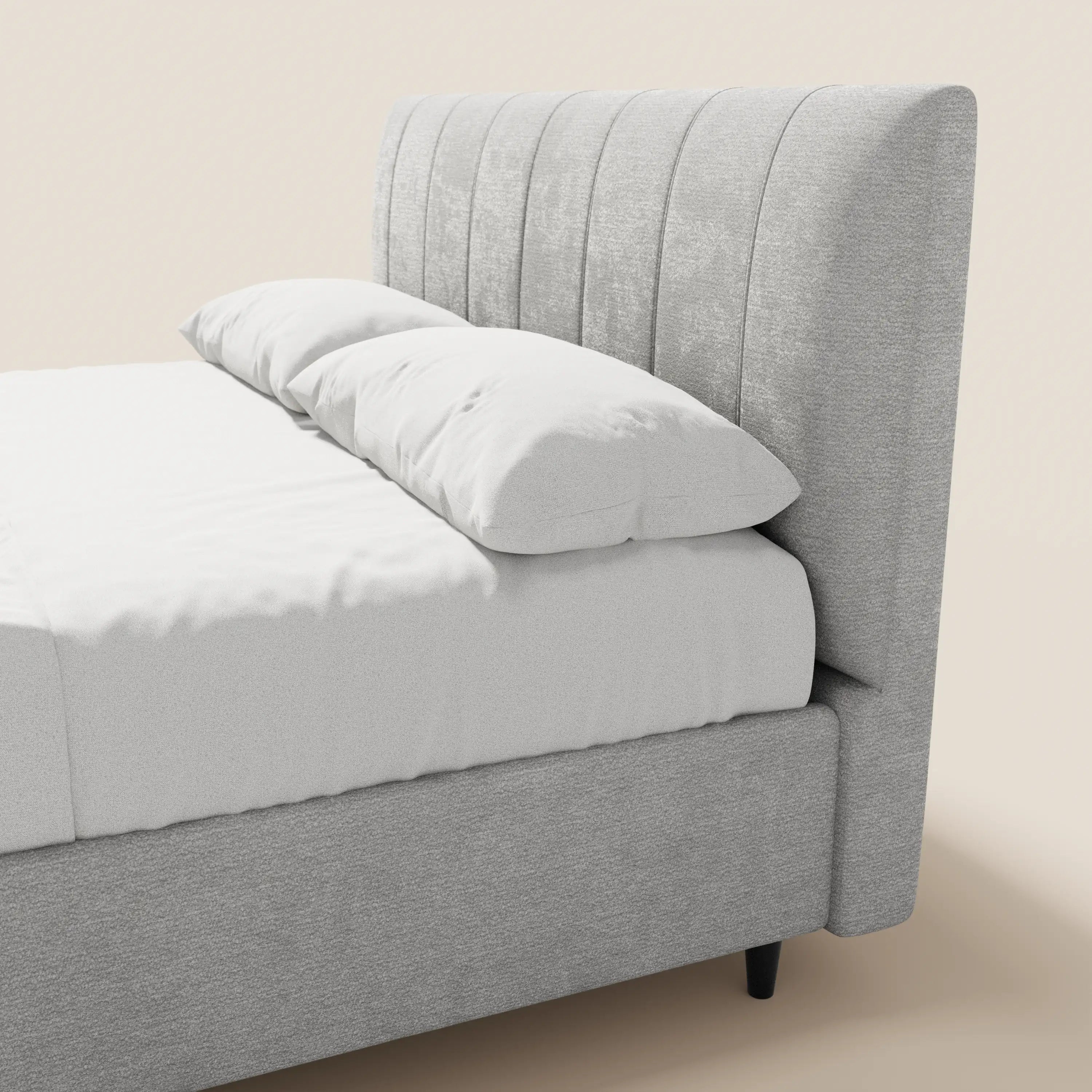 Il letto imbottito ONYX di Letti.store presenta una testiera grigio chiaro con cuciture verticali, certificata Oeko-Tex®, dotata di vano contenitore, rivestita con lenzuola e cuscini bianchi, il tutto su uno sfondo neutro che conferisce al letto un look elegante e moderno.
