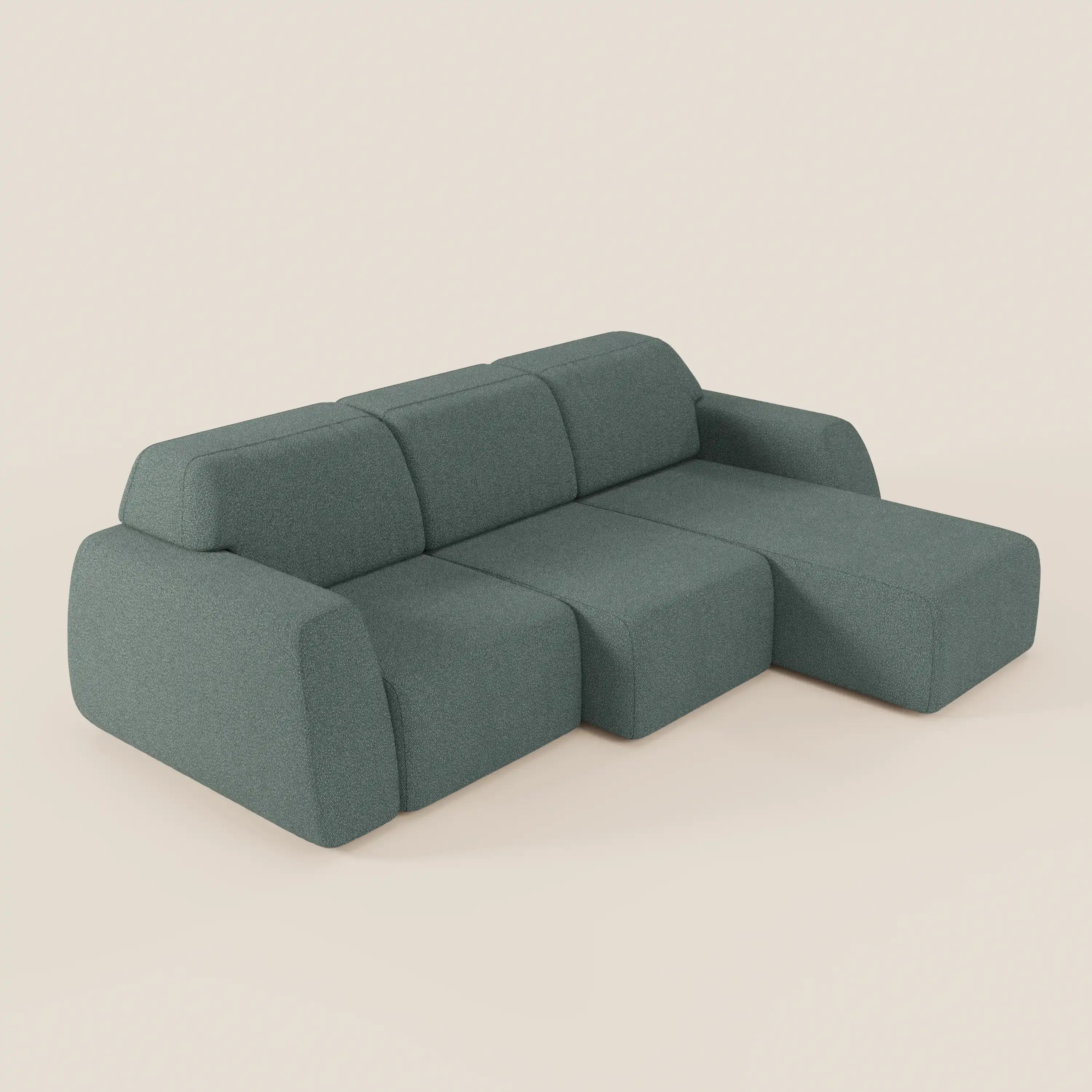 Il divano angolare Orbit di Divani.Store è caratterizzato da una chaise reversibile e da sedute allungabili in tessuto smacchiabile effetto cotone T33, con bordi arrotondati e design minimalista, proposto in verde tenue su sfondo beige chiaro.
