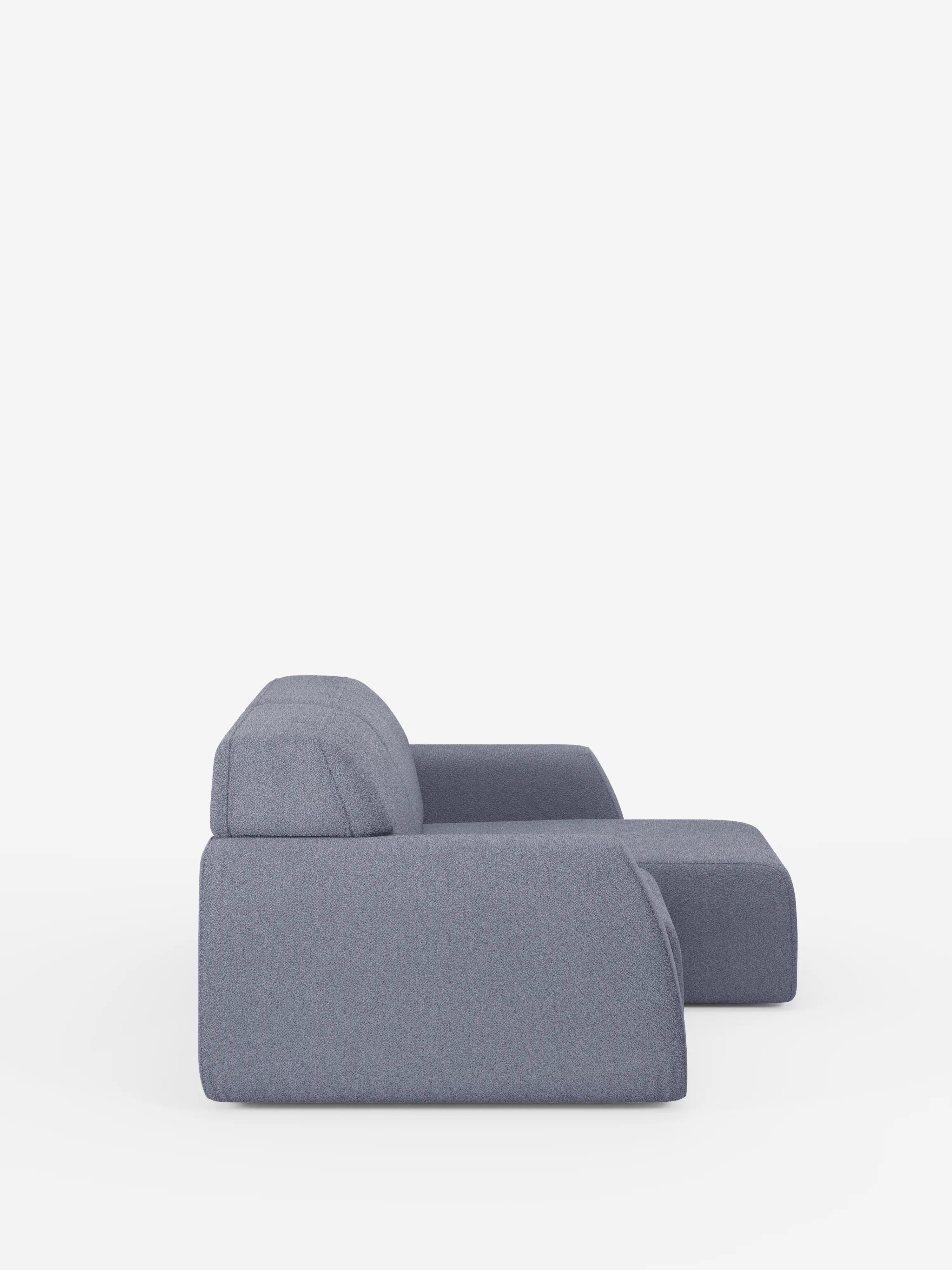 Un divano a 3 posti Orbit moderno e minimalista di Divani.Store, in una tenue tonalità di grigio-blu, caratterizzato da linee pulite, uno schienale basso e un unico cuscino di seduta che si estende fino a formare una chaise longue. Rivestito in tessuto T33 effetto cotone, sfoderabile e resistente alle macchie, è qui raffigurato di profilo su uno sfondo bianco a tinta unita.