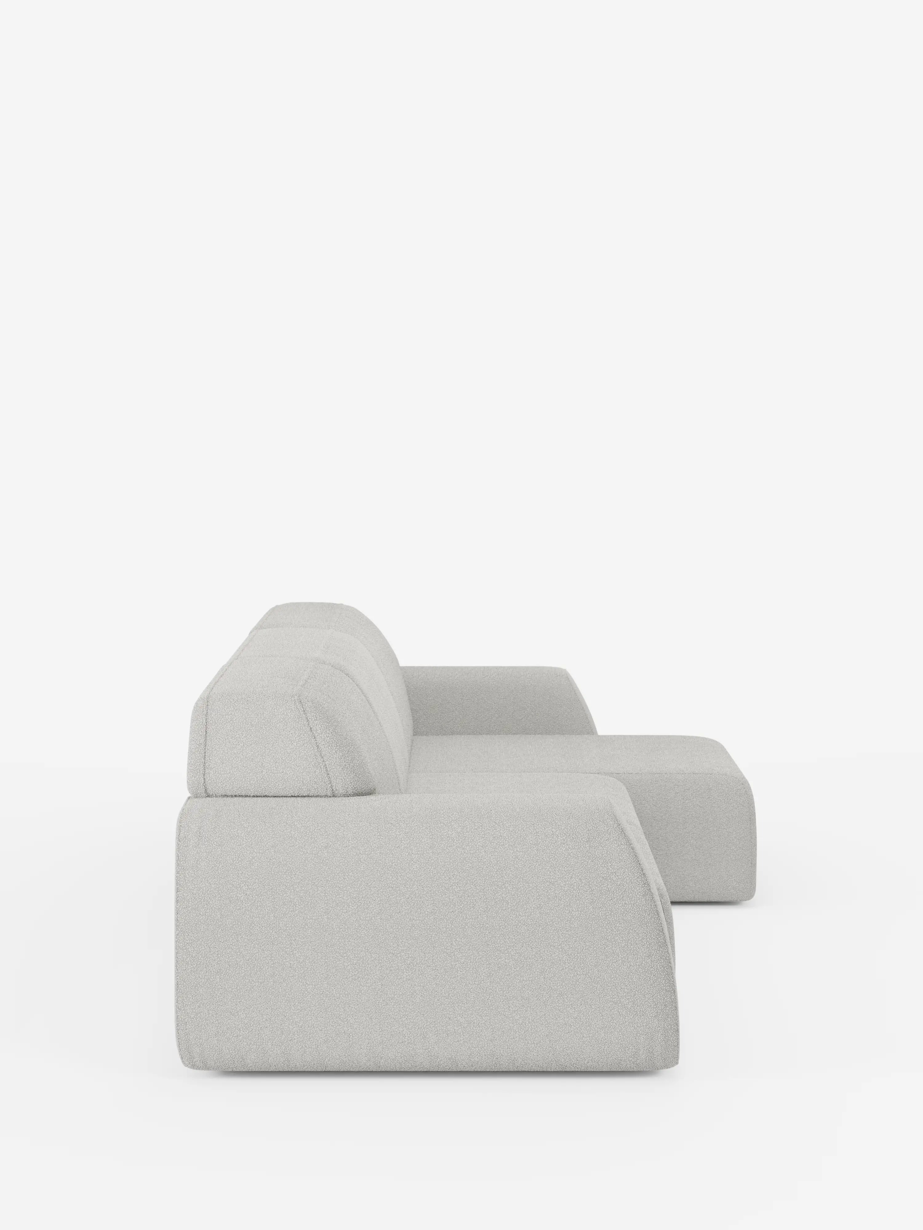 Minimalista e moderno, il divano angolare Orbit con penisola reversibile e tutte le sedute allungabili in tessuto smacchiabile effetto cotone T33 di Divani.Store è raffigurato di profilo su uno sfondo bianco. Questo divano modulare si caratterizza per le linee pulite, il profilo ribassato, il morbido rivestimento antimacchia effetto cotone e le forme geometriche con chaise longue reversibile, che gli conferiscono un look elegante e contemporaneo.