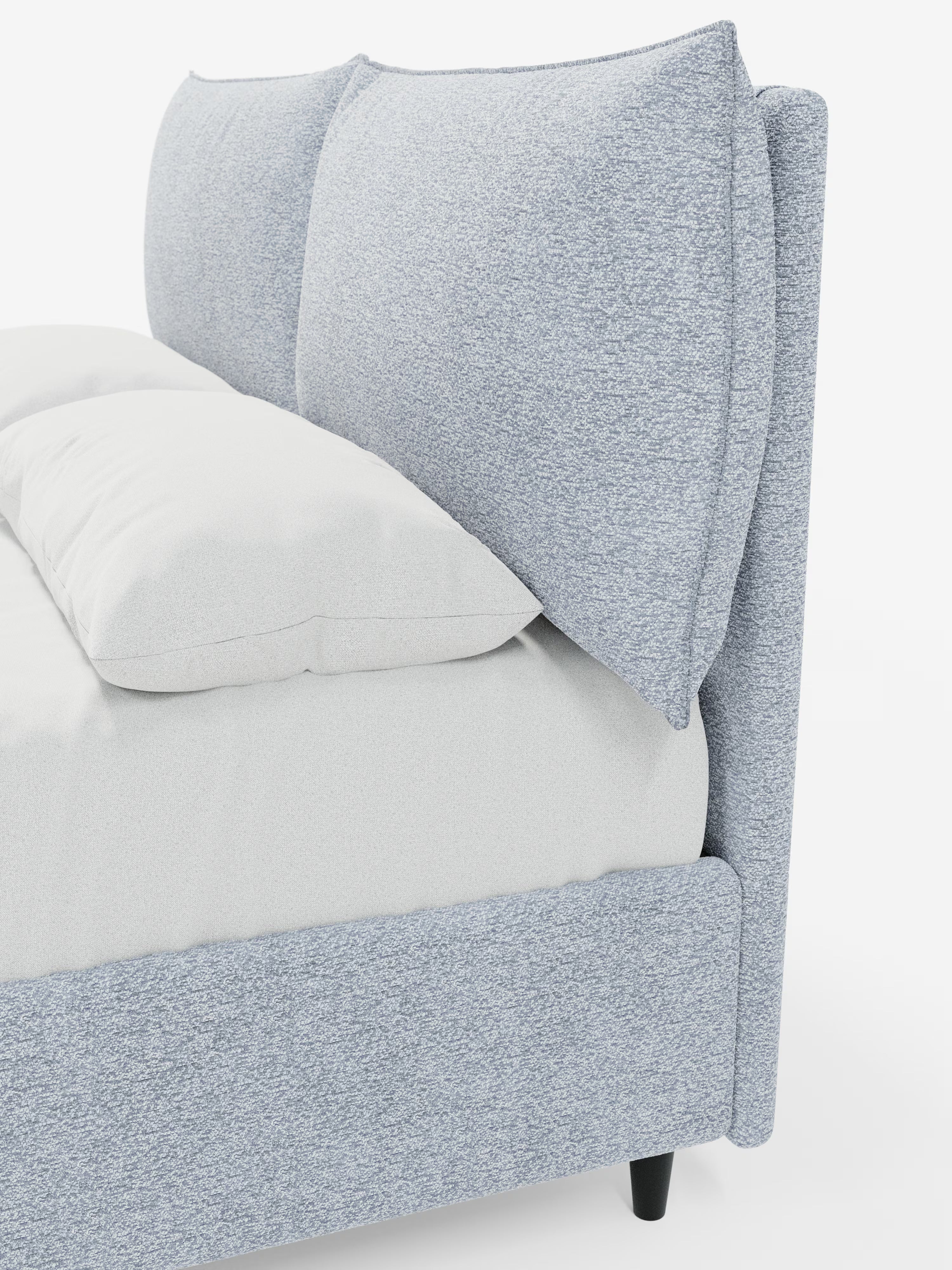 Un primo piano del letto imbottito ZAYRON con contenitore e morbidi cuscini regolabili di Letti.store, che ne mette in risalto il design moderno grazie al tessuto testurizzato azzurro certificato Oeko-Tex®, alla testiera imbottita con due grandi cuscini regolabili e alla biancheria da letto bianca. Il letto presenta gambe affusolate nere ed è posizionato su uno sfondo bianco.