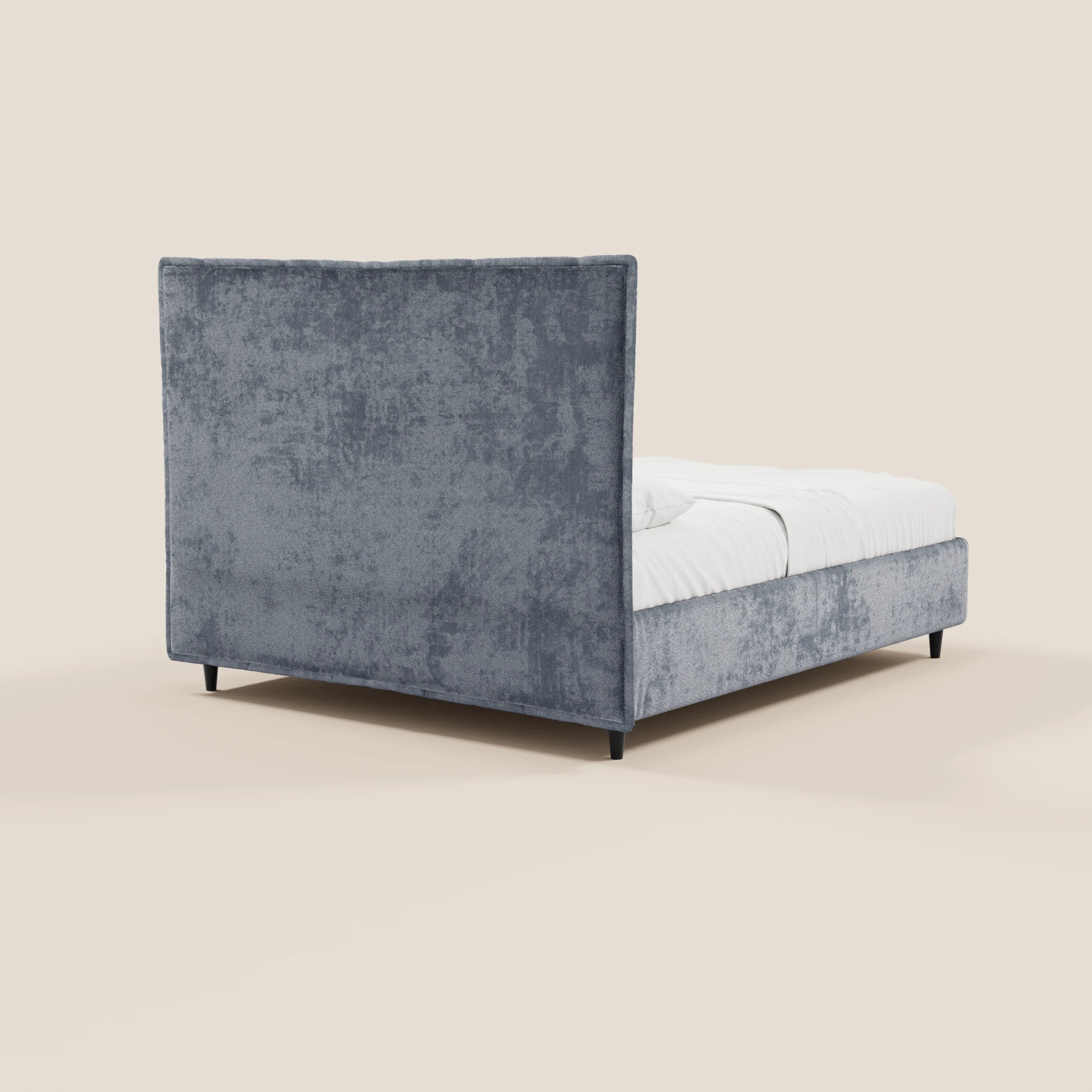 Il letto imbottito AURO con contenitore di Letti.store presenta una testiera alta e rettangolare con rivestimento capitonné in ciniglia certificata Oeko-Tex®, pannelli laterali, biancheria da letto bianca e gambe nere. Nell’immagine è raffigurato inclinato su uno sfondo beige chiaro a tinta unita.