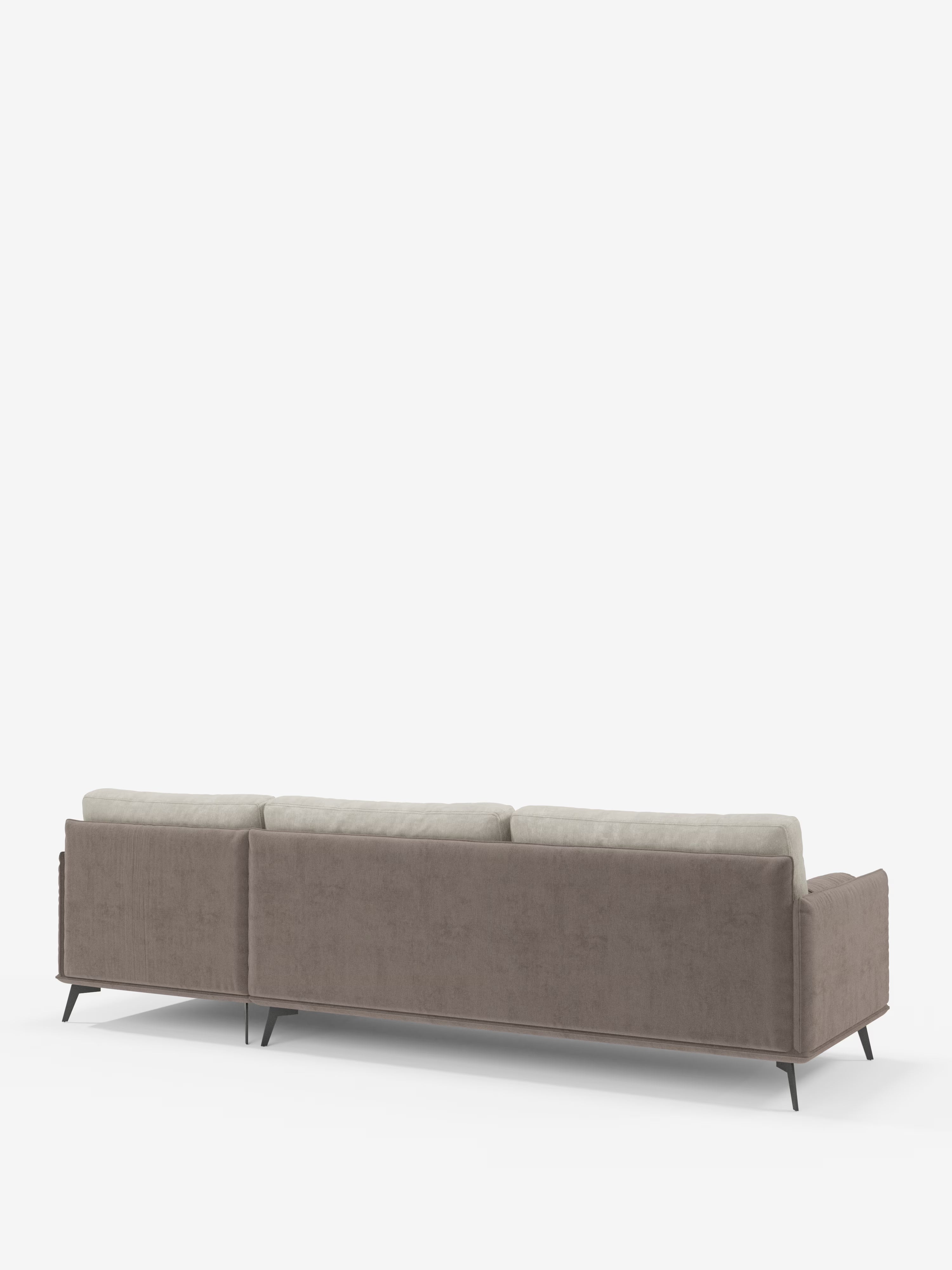 Una vista posteriore del divano angolare bicolore Basalto con penisola e base in metallo di Divani.Store, che presenta schienali grigio chiaro imbottiti in piuma e una struttura color tortora rivestita in tessuto T31 antimacchia. Il divano poggia su sottili gambe angolari in metallo nero su uno sfondo bianco a tinta unita, che ne sottolineano il design moderno e minimalista.