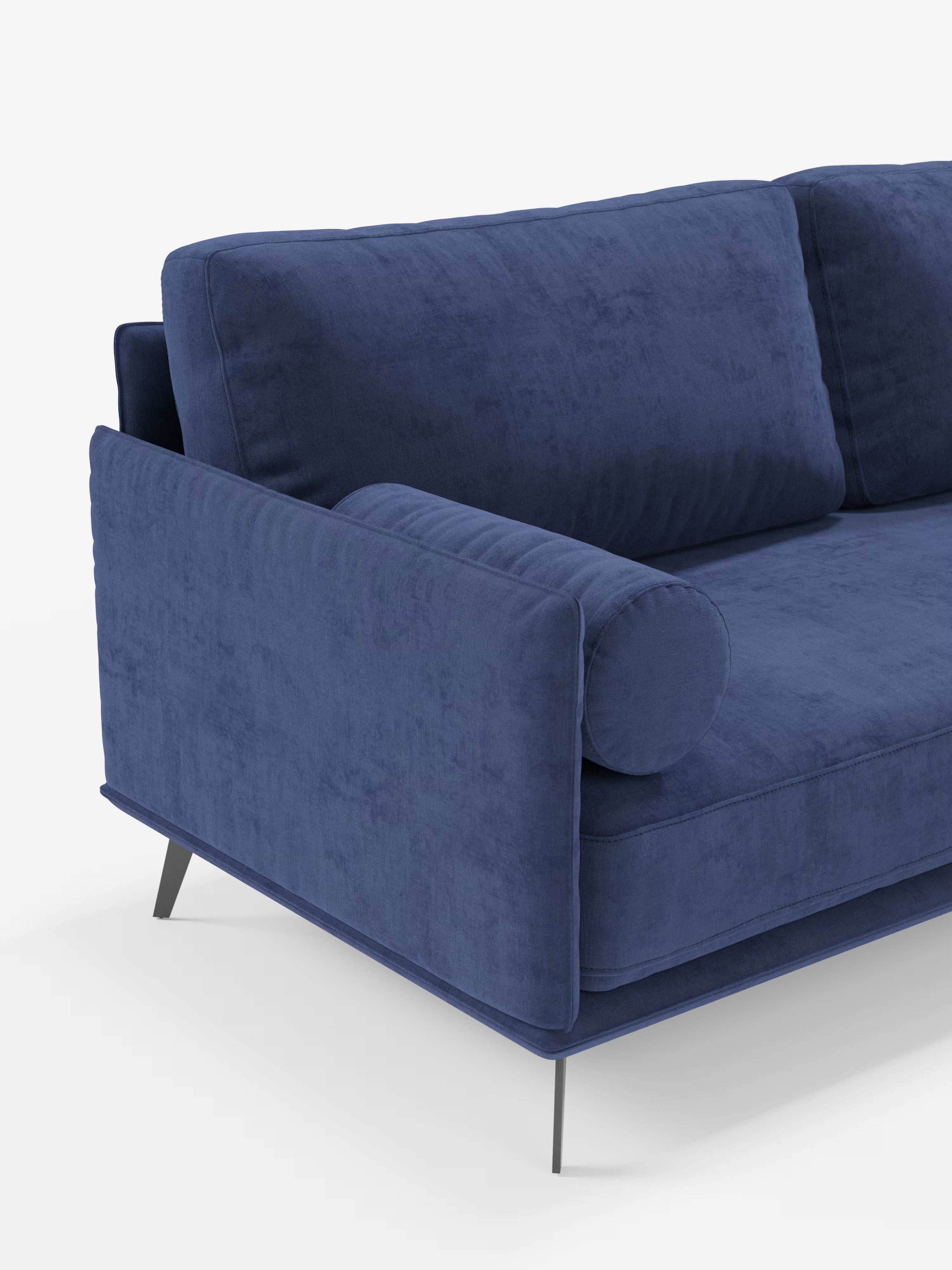 Il divano lineare Basalto a 2 o 3 posti con seduta unica e base in metallo, rivestito in tessuto smacchiabile T31 di Divani.Store, è presentato in una moderna finitura in velluto blu con morbidi cuscini e un cuscino cilindrico su un bracciolo. Questo divano minimalista presenta linee pulite, una morbida trama del tessuto e sottili gambe angolate in metallo nero, che risaltano su uno sfondo bianco a tinta unita. È visibile solo un lato del divano.