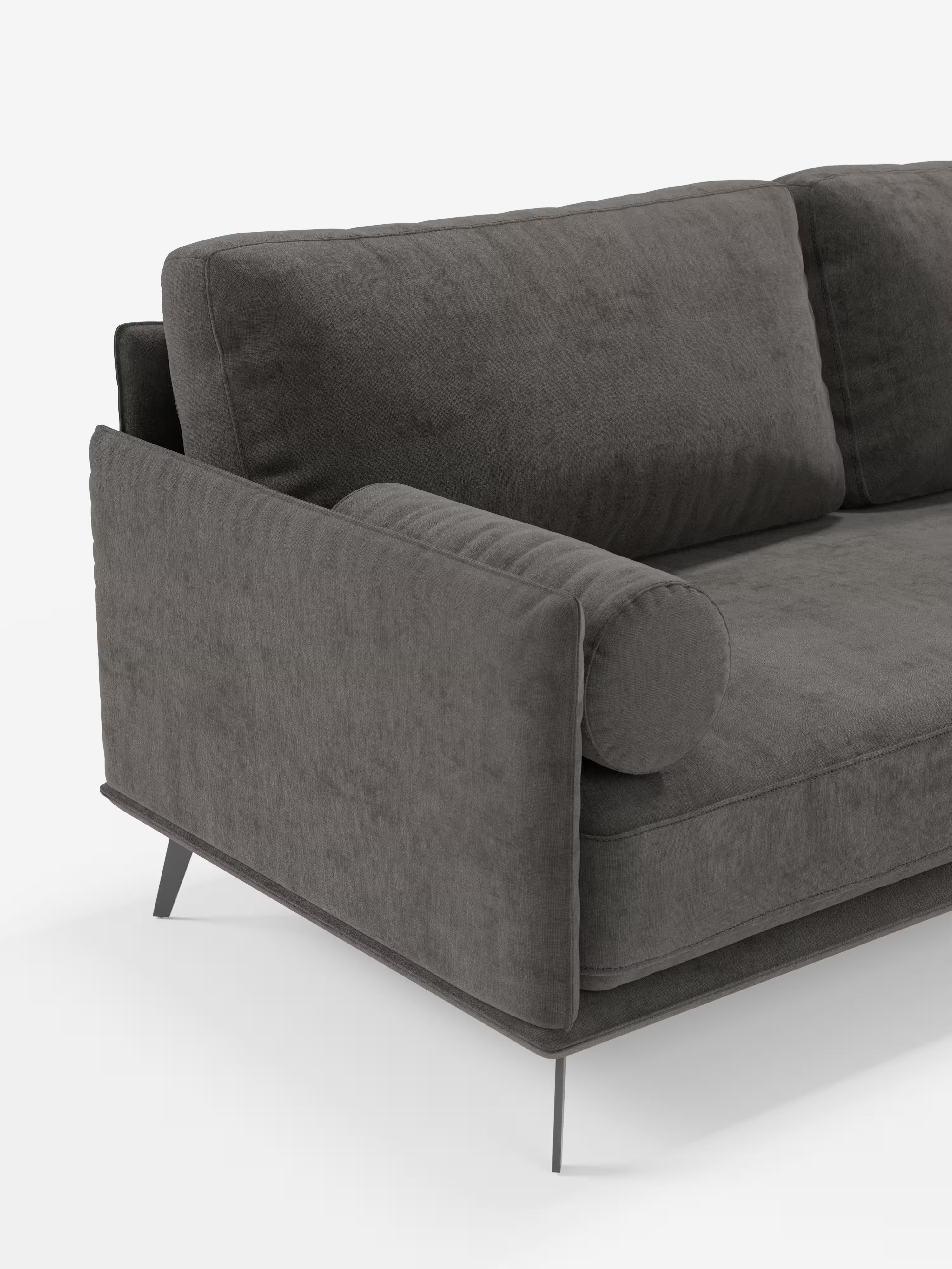 Un primo piano del divano lineare Basalto a 2 o 3 posti di Divani.Store, presentato in un moderno tessuto T31 grigio scuro smacchiabile. Questo divano minimalista è caratterizzato da un esclusivo cuscino di seduta unico, braccioli squadrati e un cuscino cilindrico coordinato. Appoggiato su sottili gambe metalliche angolate (base in metallo), il suo rivestimento sfoderabile ne facilita la manutenzione, mentre lo sfondo bianco a tinta unita ne accentua il design elegante.