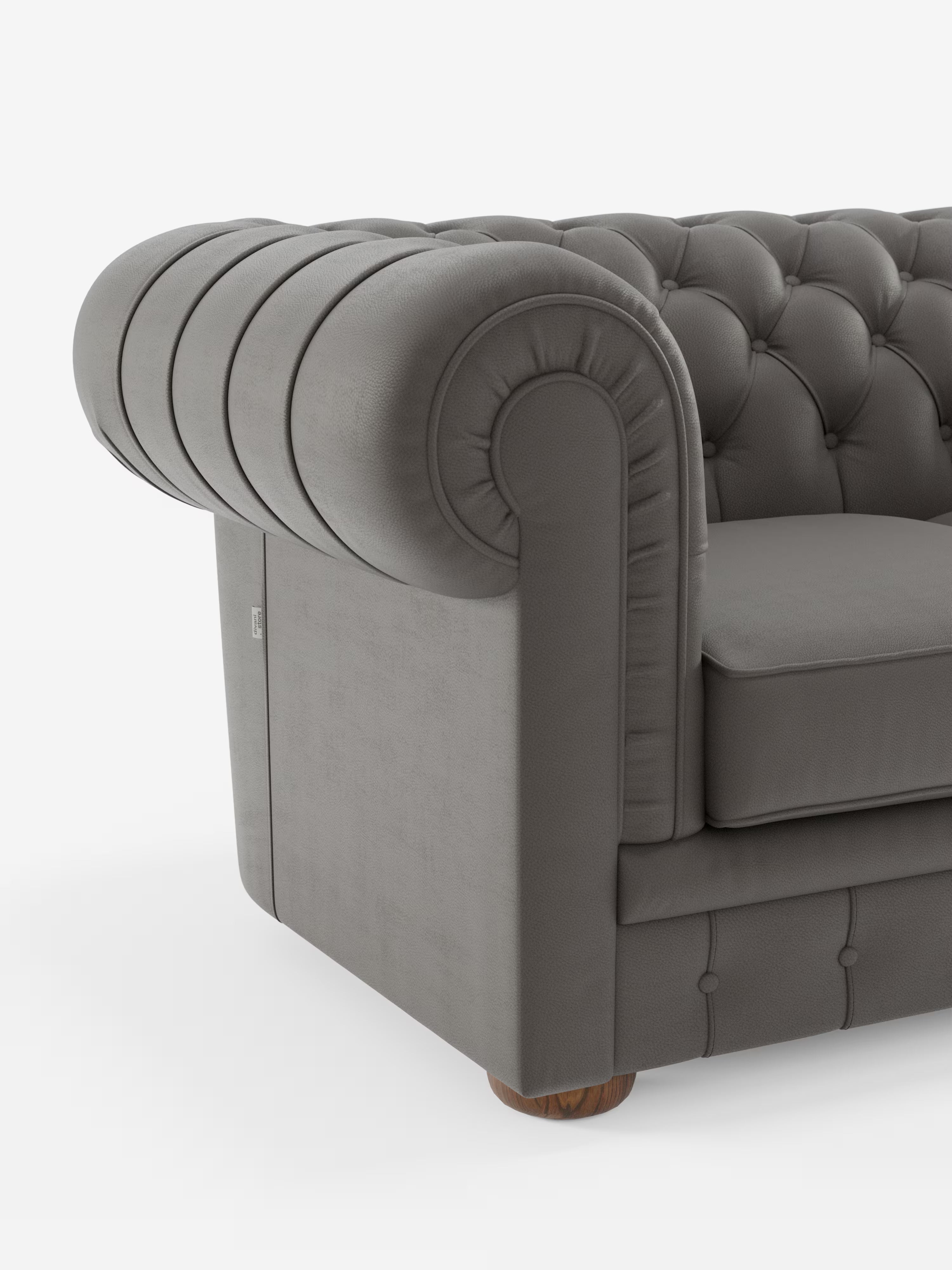 Primo piano del bracciolo sinistro del divano Chester 4 Posti 3 sedute in Vera Pelle – Chesterfield Capitonné Artigianale di Divani.Store, che mette in risalto il rivestimento con profonda trapuntatura a bottoni e il dettaglio arrotondato e arrotolato del bracciolo. Realizzato in Italia, questo divano grigio poggia su una piccola gamba rotonda in legno, mentre il rivestimento in vera pelle presenta una finitura morbida e opaca. Immagine su sfondo bianco.