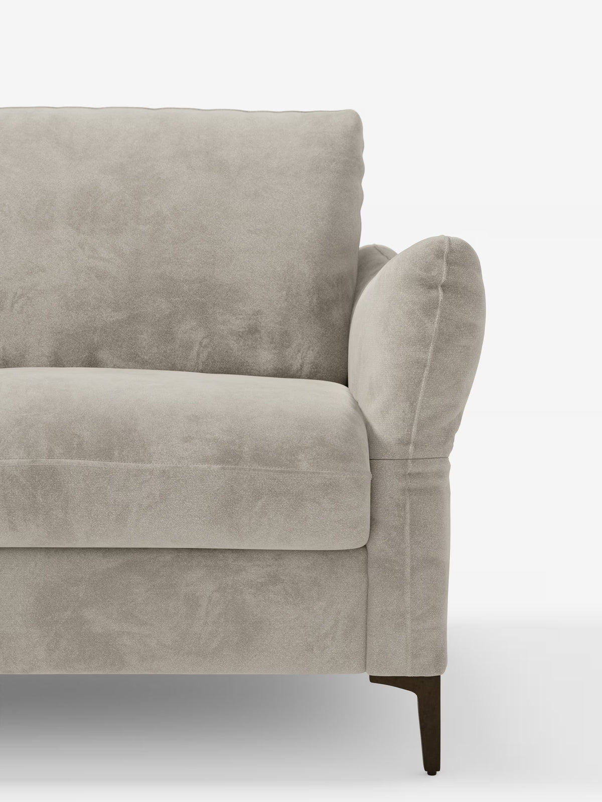 Un primo piano del divano letto Dalia, disponibile nelle versioni a 2, 3 e 4 posti, rivestito in tessuto vellutato chiaro, con materasso H18, realizzato in moderno tessuto vellutino antimacchia T30 di Divani.Store, caratterizzato da un'imbottitura morbida, braccioli arrotondati e gambe in legno scuro. Su uno sfondo bianco a tinta unita è visibile solo la metà sinistra di questo versatile divano letto.