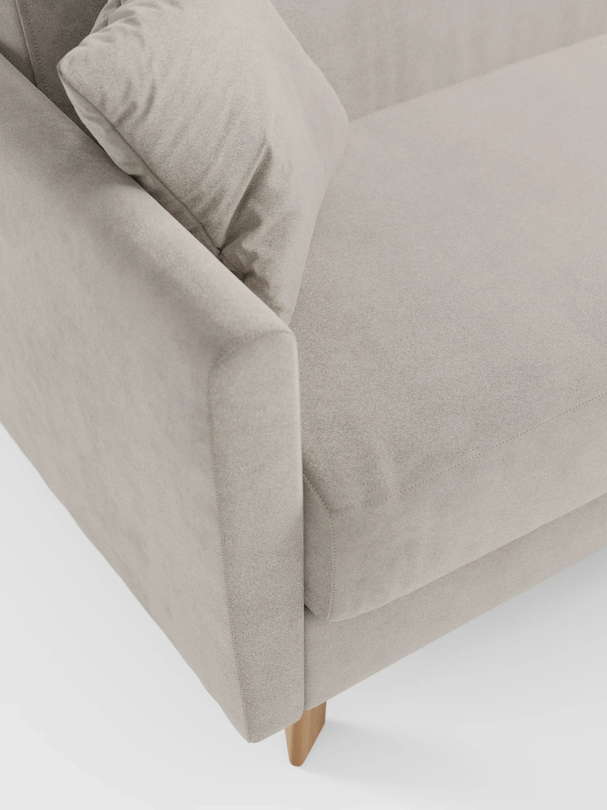 Primo piano del divano letto Francy con poggiatesta regolabili di Divani.Store, rivestito in elegante tessuto T30 resistente alle macchie. L'immagine mette in risalto il bracciolo angolato di questo moderno divano beige, con cuscini dello schienale e della seduta abbinati. Questo versatile divano a due posti è dotato di rivestimenti completamente sfoderabili e poggia su gambe in legno chiaro su uno sfondo bianco a tinta unita. Il design complessivo è minimalista e pulito.