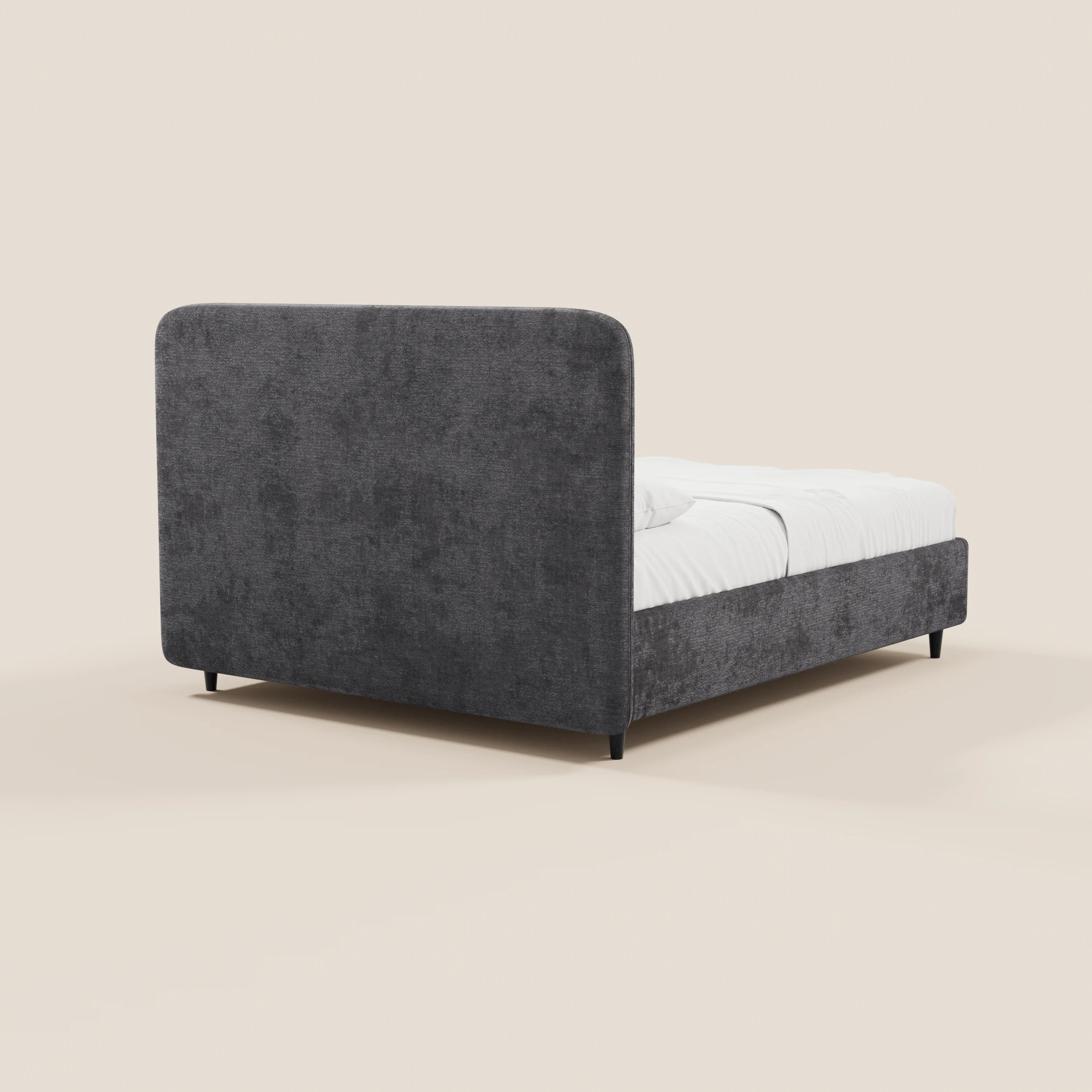 Il letto imbottito KAELOS minimal di Letti.store è rivestito in tessuto ciniglia grigio scuro, presenta una testiera alta e arrotondata, pannelli laterali bassi, gambe alte nere e un vano contenitore; nella foto è raffigurato con biancheria da letto bianca su uno sfondo beige chiaro.