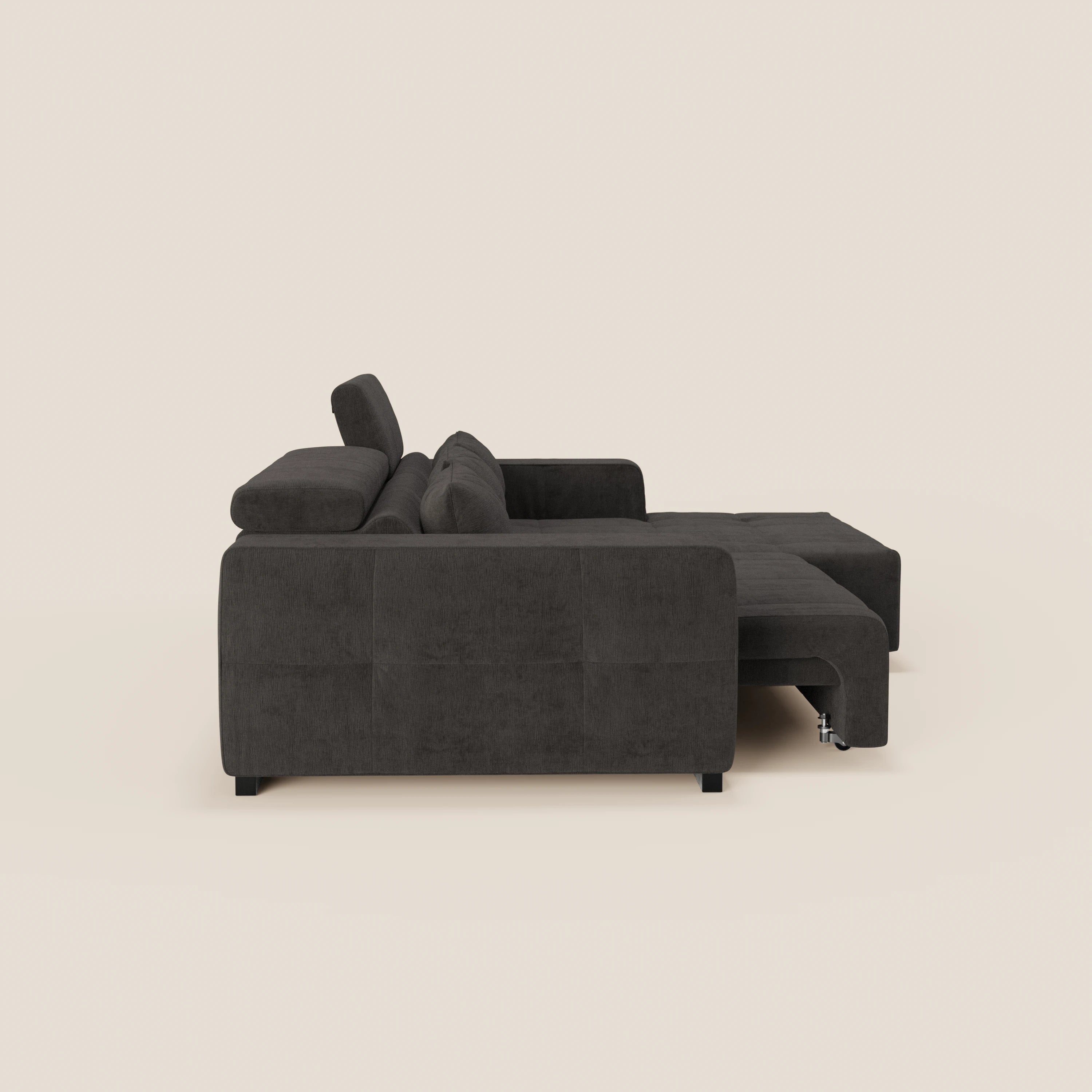 Una vista laterale del Monarch Divano angolare con penisola e Relax Elettrico di Divani.Store, grigio scuro, su uno sfondo beige chiaro, con ampi braccioli, cuscini morbidi, chaise longue destra e gambe corte nere.