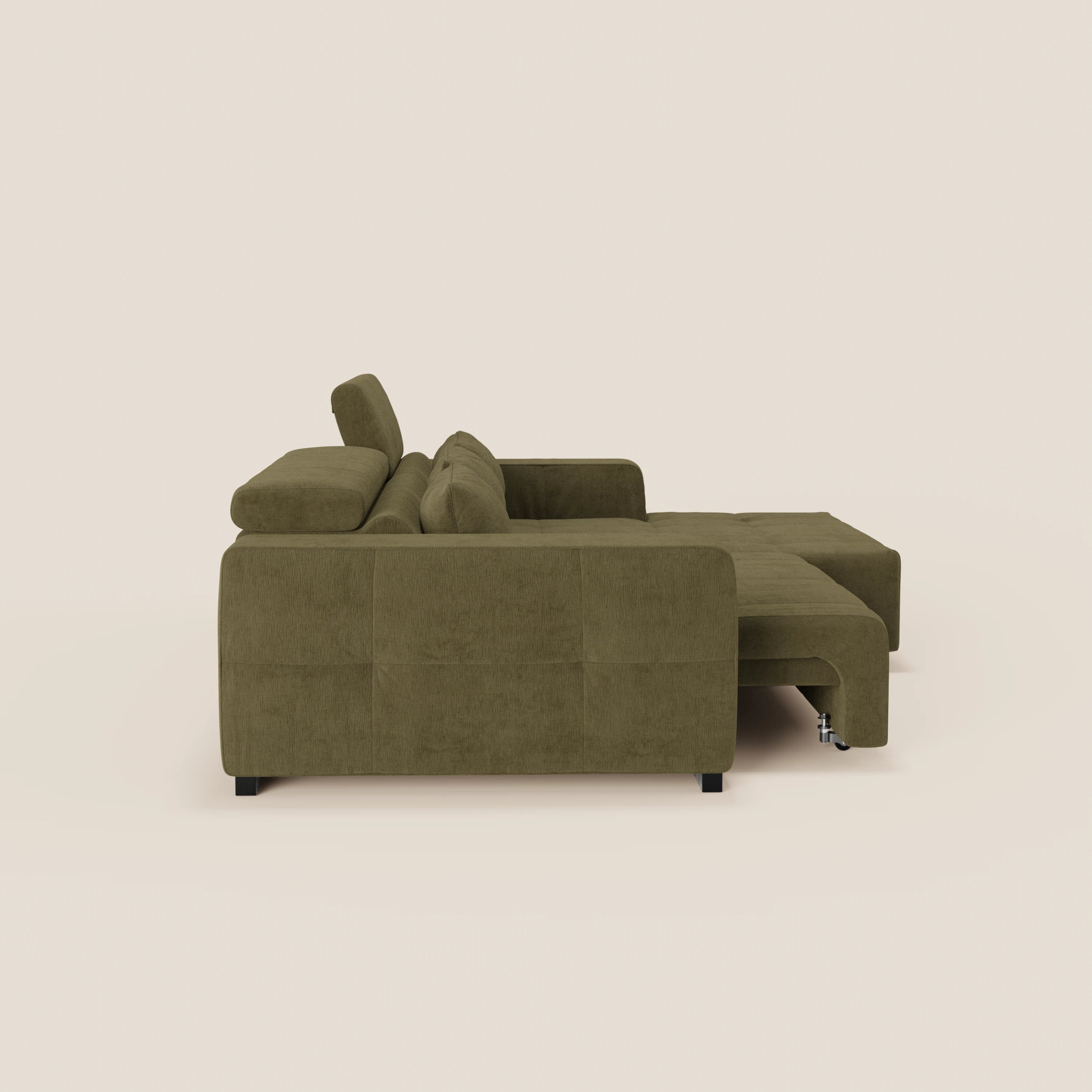 Il divano Monarch angolare con penisola e Relax Elettrico di Divani.Store è presentato lateralmente, con ampi braccioli, cuscini trapuntati, poggiatesta reclinabili e chaise lounge allungata. Su uno sfondo beige chiaro.