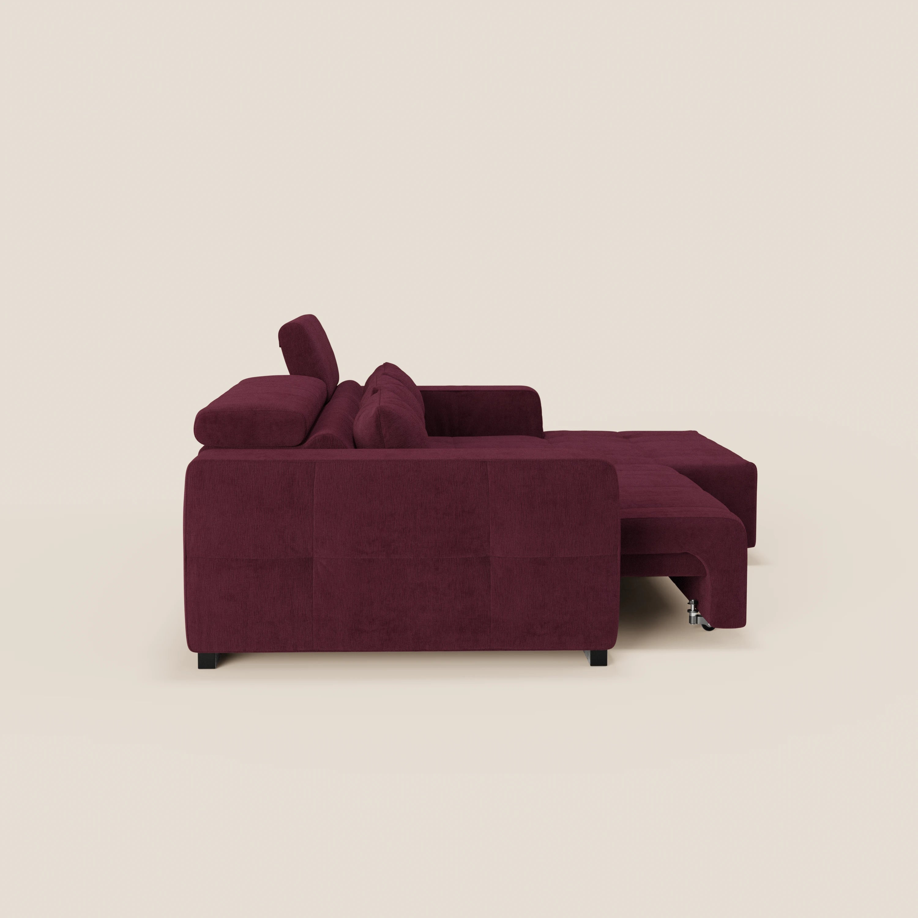 Il Monarch Divano angolare con penisola di Divani.Store in tessuto smacchiabile T31, mostrato lateralmente, ha linee pulite, braccioli larghi, chaise longue destra, poggiatesta reclinabili e relax elettrico per sedute allungabili su fondo crema.