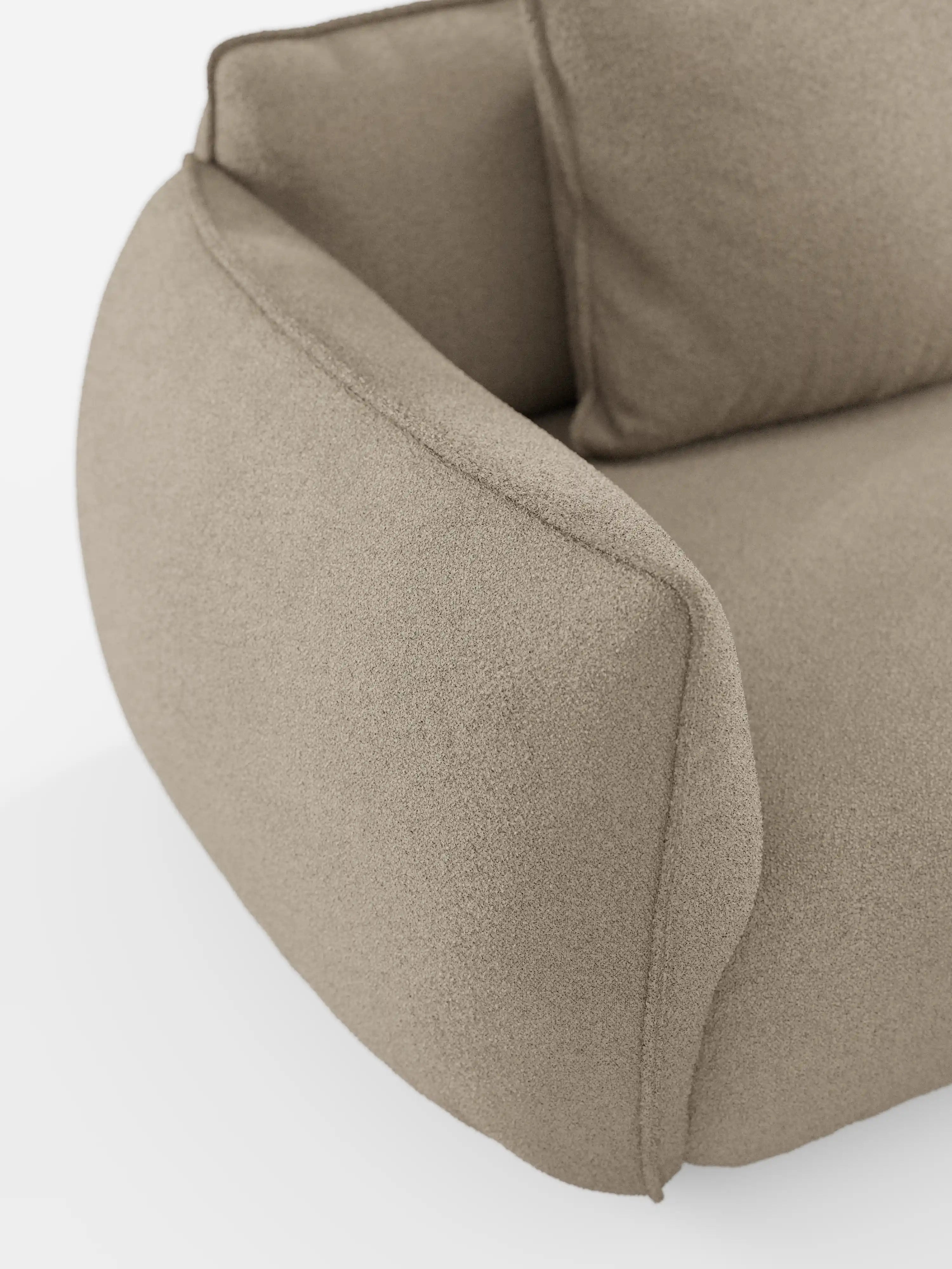 Primo piano del bracciolo e dello schienale del divano modulare a 3 posti “Nimbus” di Divani.Store, rivestito in morbido tessuto T33 effetto cotone, resistente alle macchie. Il design moderno è caratterizzato da curve morbide e da una texture soffice. Sullo sfondo bianco, risaltano la tonalità neutra e la silhouette arrotondata del divano.