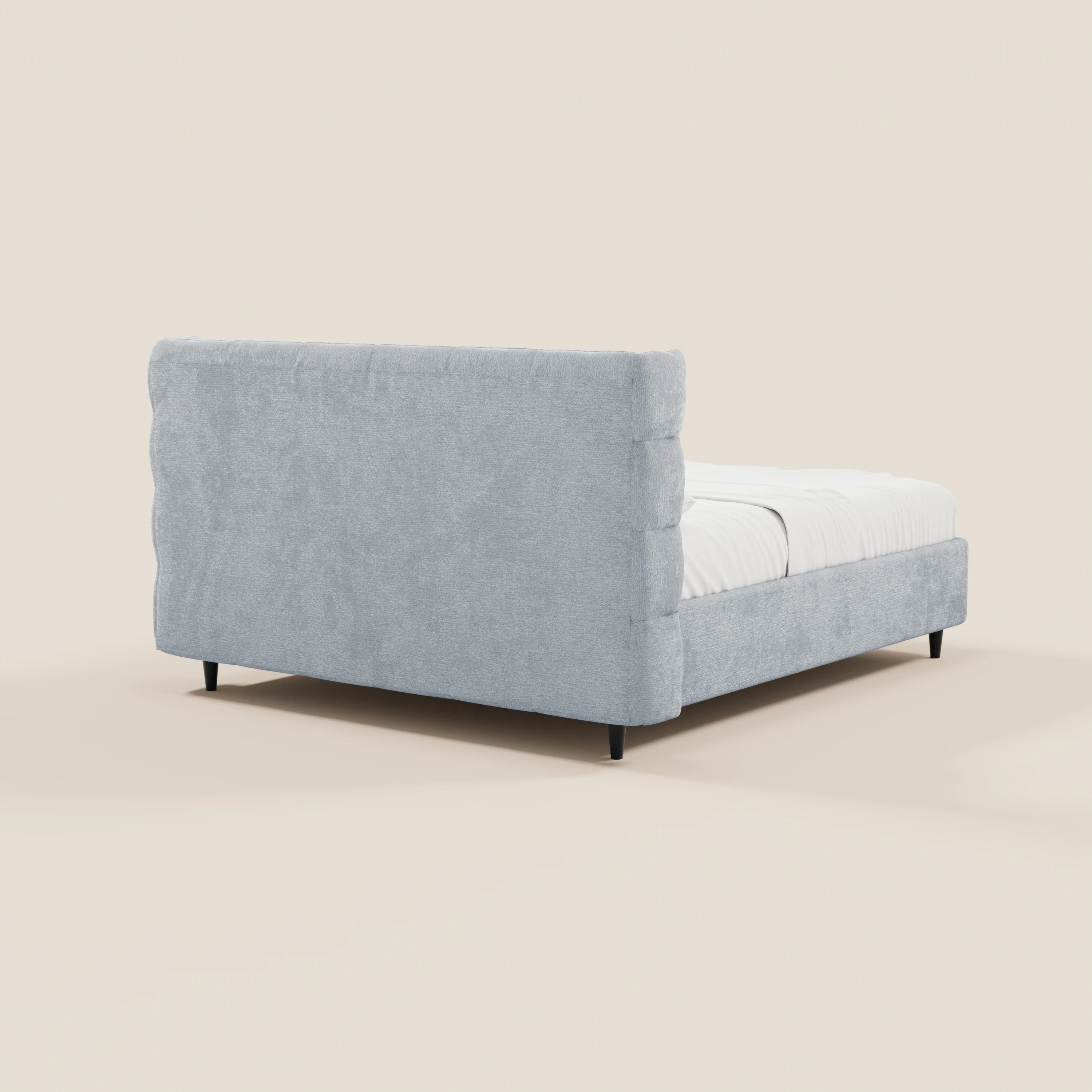 Il letto imbottito RAGNAR di Letti.store è caratterizzato da un tessuto grigio chiaro certificato Oeko-Tex®, una testiera avvolgente con lavorazione capitonné, gambe corte nere e un vano contenitore. La biancheria da letto bianca e uno sfondo beige a tinta unita completano il look moderno.