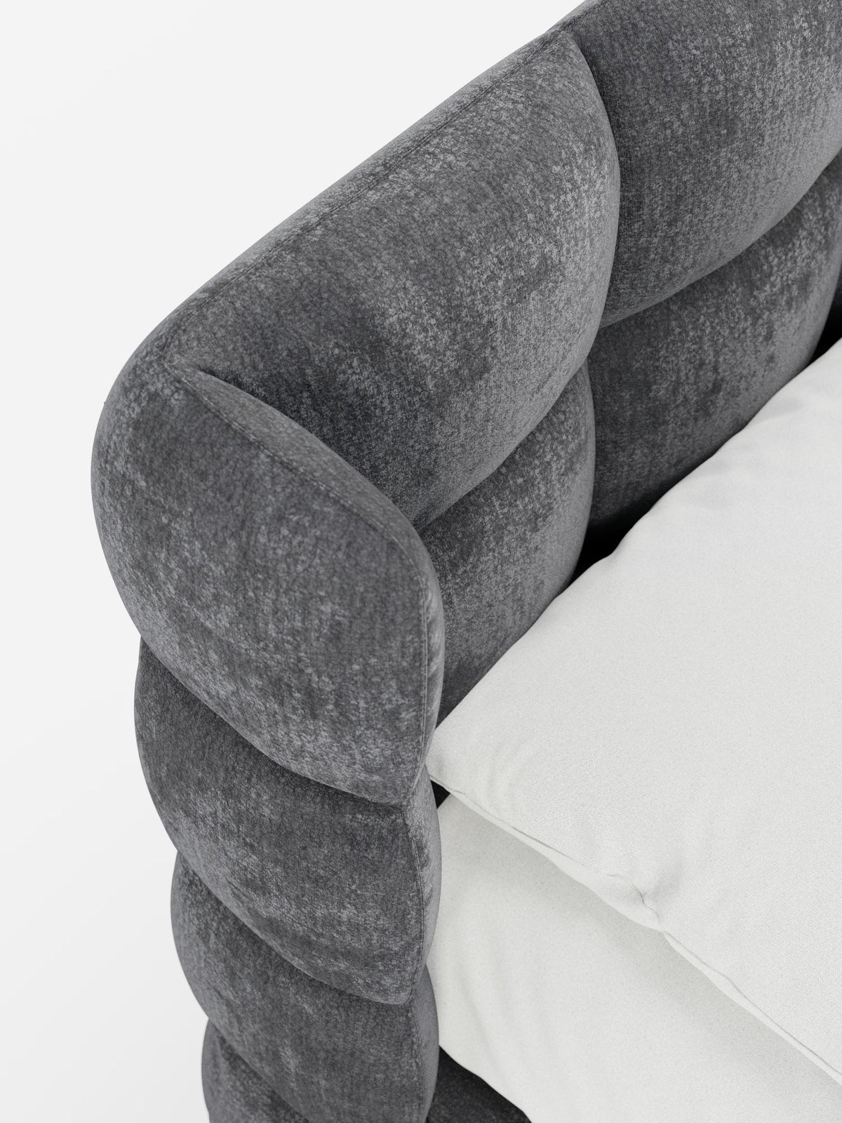 Primo piano del letto imbottito RAGNAR con contenitore e testiera capitonné avvolgente di Letti.store, caratterizzato da un elegante e soffice tessuto grigio scuro certificato Oeko-Tex®. La testiera arrotondata e trapuntata presenta un classico design capitonné, impreziosita da un cuscino di seduta bianco a contrasto. I materiali morbidi e le linee moderne creano un look accogliente ma allo stesso tempo elegante sullo sfondo bianco a tinta unita.