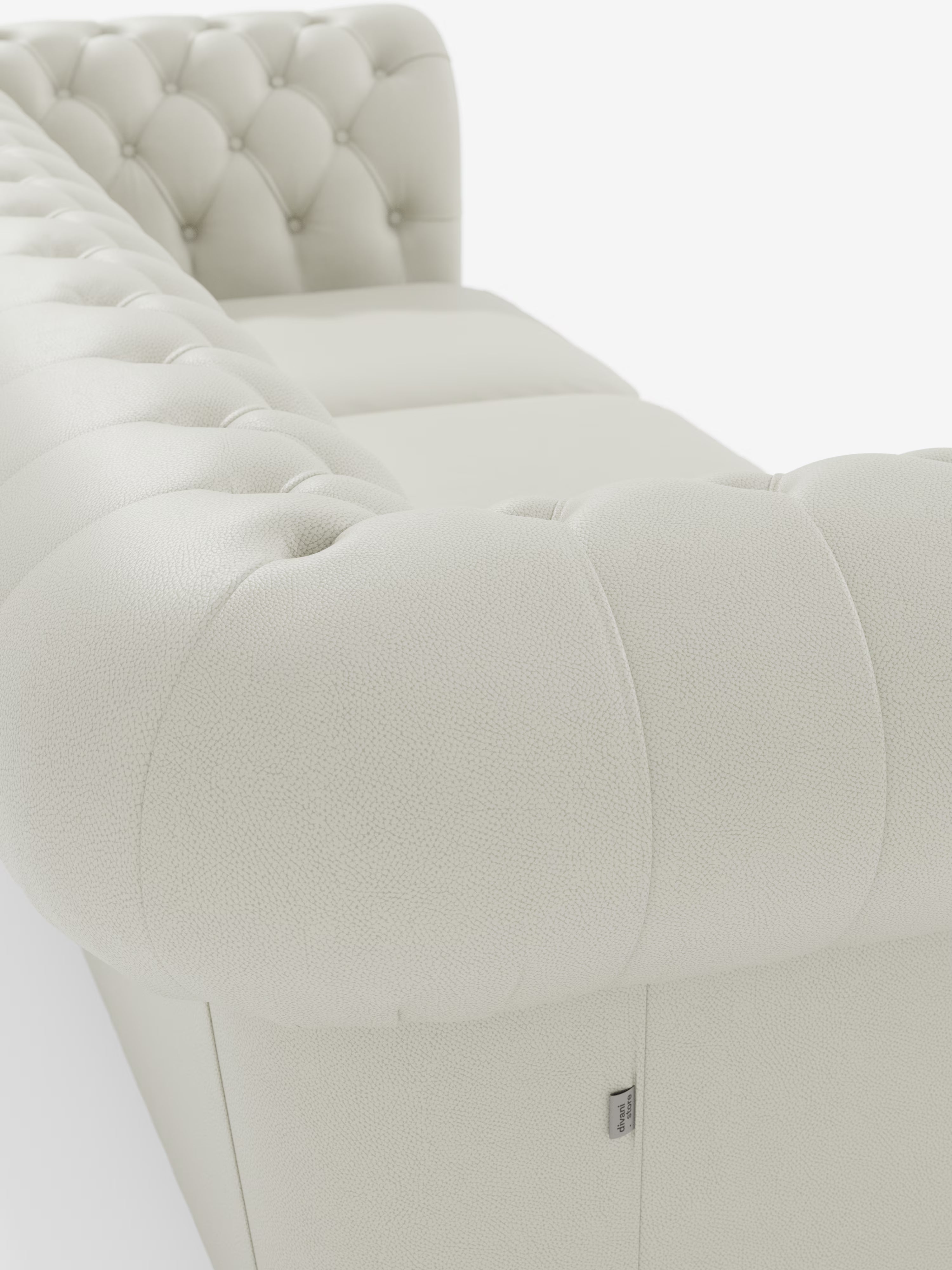 Primo piano del divano Chester 4 Posti 3 sedute color crema chiaro in vera pelle – Chesterfield Capitonné Artigianale di Divani.Store, caratterizzato da braccioli arrotondati e da una superficie in pelle trapuntata con cuciture dettagliate e bottoni decorativi distintivi che richiamano il classico Chesterfield. Il rivestimento in vera pelle è ben visibile, insieme a una piccola etichetta in tessuto sul lato inferiore. Lo sfondo è bianco a tinta unita.