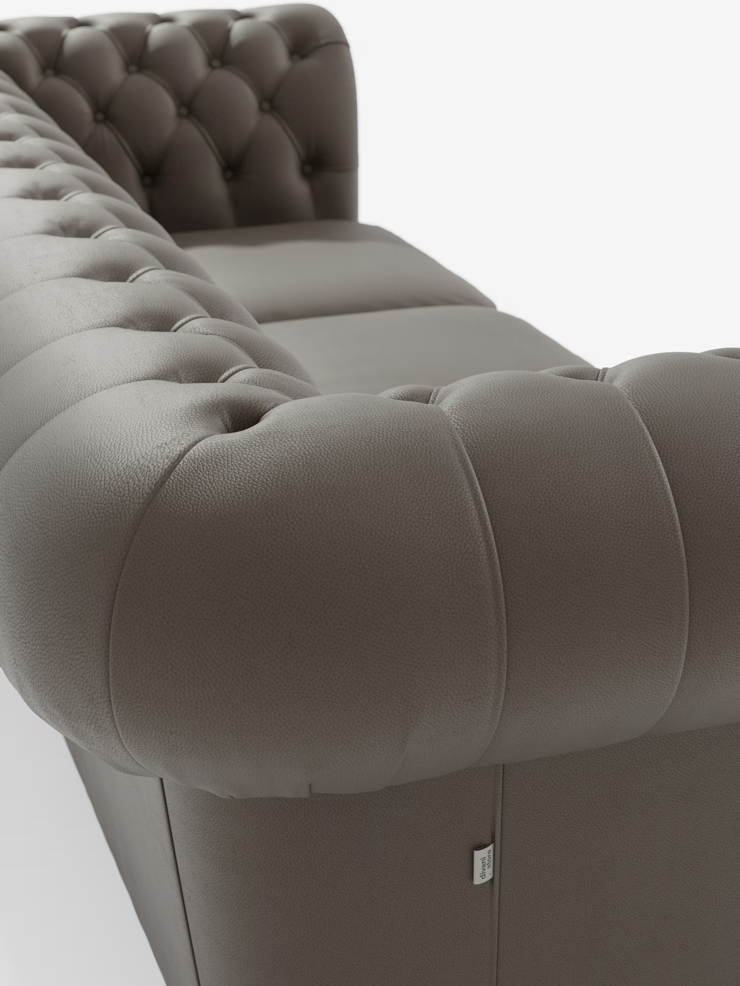 Primo piano del Chester 4 Posti 3 sedute in Vera Pelle – Chesterfield Capitonné Artigianale di Divani.Store, che presenta un divano in pelle grigia con schienale e braccioli capitonné. Risaltano il morbido rivestimento in vera pelle dalla texture particolare e i dettagli delle profonde bottoniature, mentre una vista obliqua mette in risalto il bracciolo imbottito e una parte della seduta su sfondo bianco. Realizzato a mano con maestria in Italia.