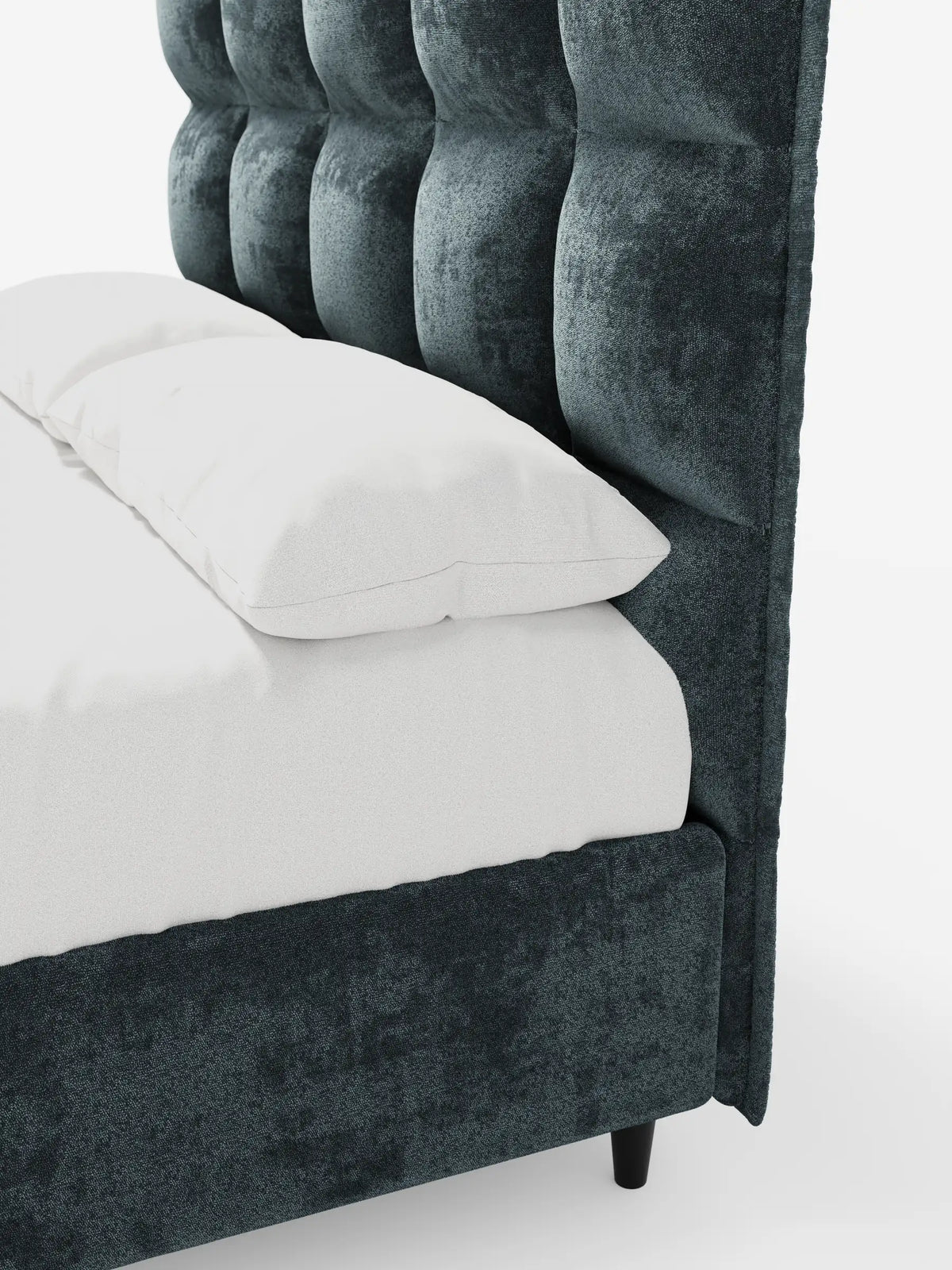 Un letto imbottito AURO in velluto blu scuro con struttura a vista e testiera alta capitonné in ciniglia Oeko-Tex®, rivestito con lenzuola bianche immacolate su uno sfondo bianco a tinta unita.