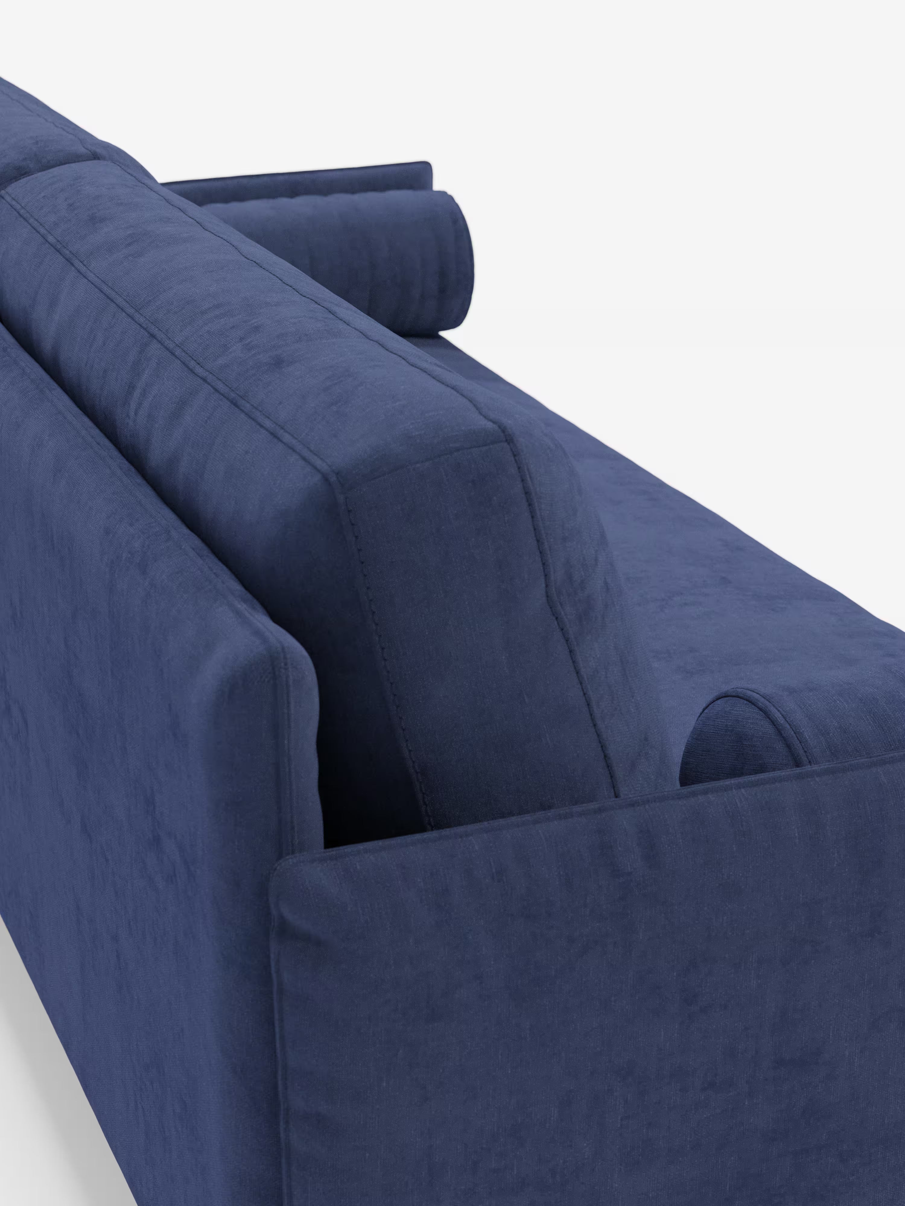 Un primo piano dello schienale e del bracciolo del divano lineare Basalto a 2 o 3 posti con seduta unica e base in metallo, rivestito in tessuto smacchiabile T31 di Divani.Store. Questo divano minimalista, qui presentato con rivestimento blu scuro, è caratterizzato da cuscini dello schienale rettangolari e rigidi e include cuscini cilindrici alle due estremità, il tutto sostenuto da una robusta base in metallo, che fa da contrappunto a uno sfondo bianco a tinta unita.